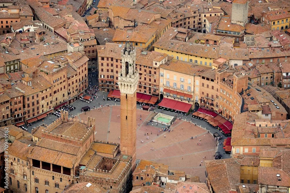 Aerial view of Piazza della Signoria in Florence, Italy, featuring the Fontana del Nettuno fountain, Loggia della Signoria, and surrounding historic buildings with red-tiled roofs.