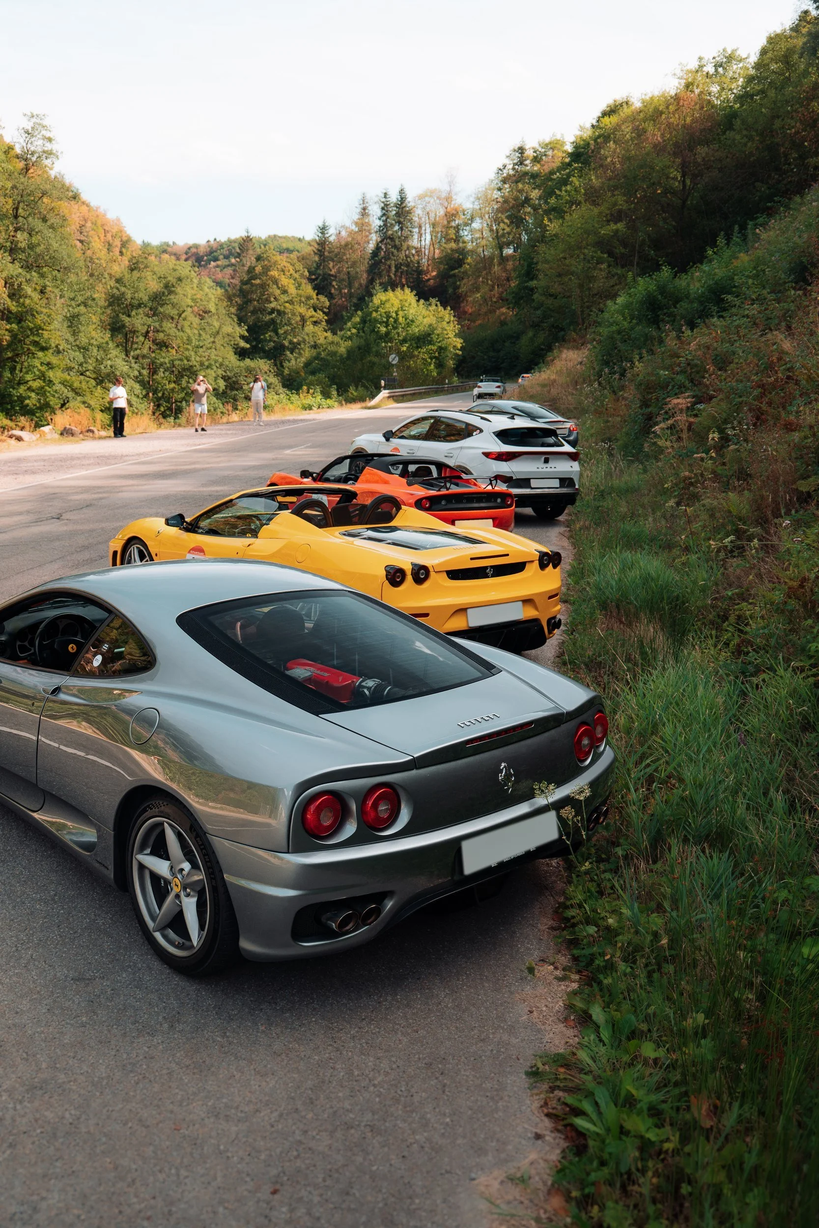 Silberner Ferrari 360 und der Rest des Konvois an einer Waldstrasse geparkt, bei einer früheren One Tank Tour