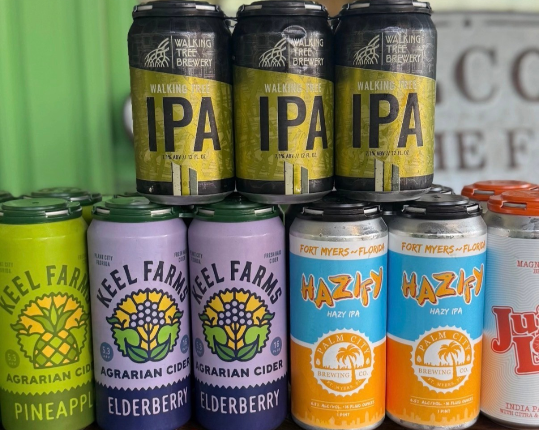 Cans of beer and cider on a store shelf, including Walking Tree IPA, Keel Farms Agrarian Cider Elderberry, Hazify Hazy IPA, and Juicy Lucy India Pale Ale.