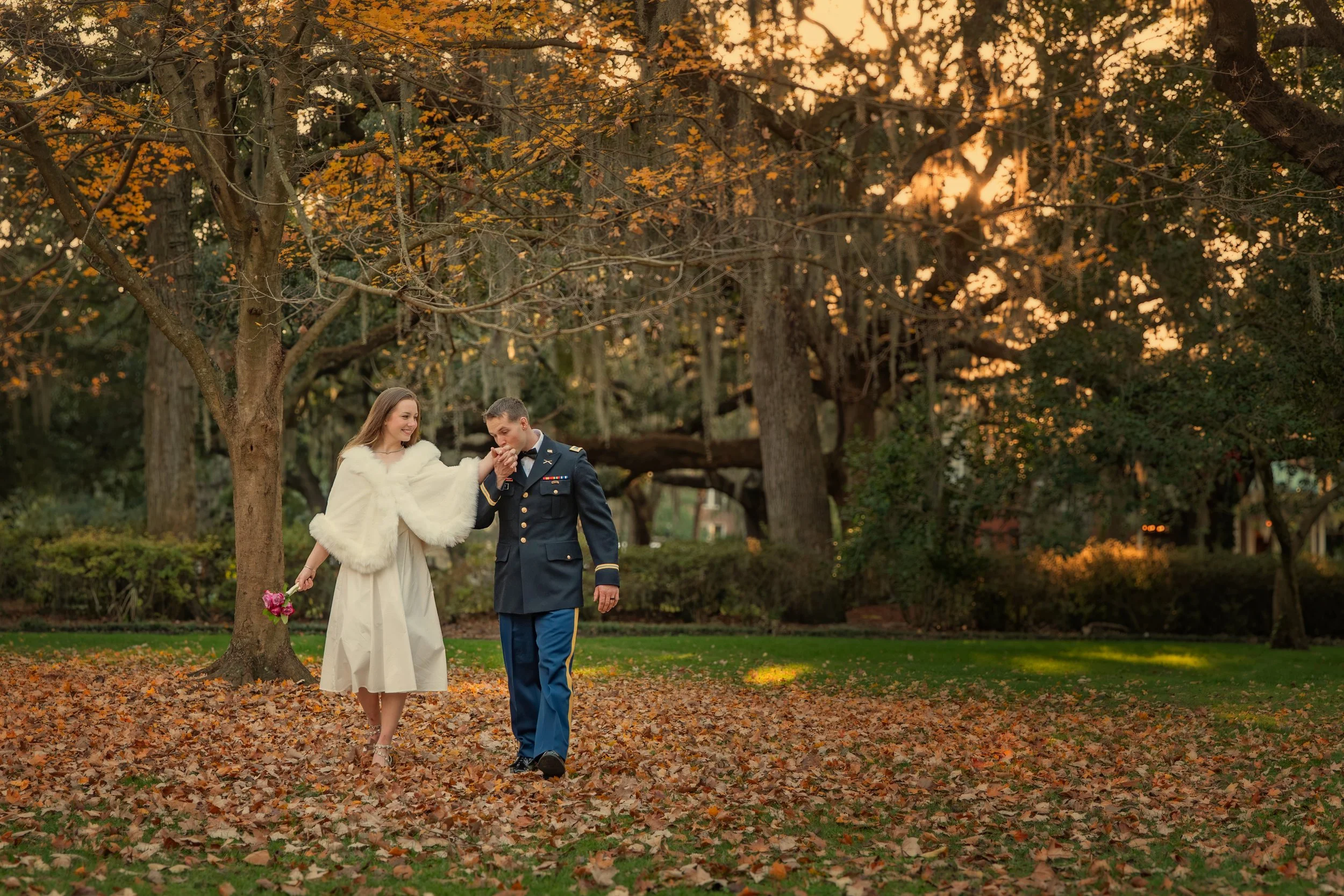 Bride and groom walk together beneath colorful fall leaves in Forsyth Park during an elegant autumn wedding in Savannah, Georgia.
