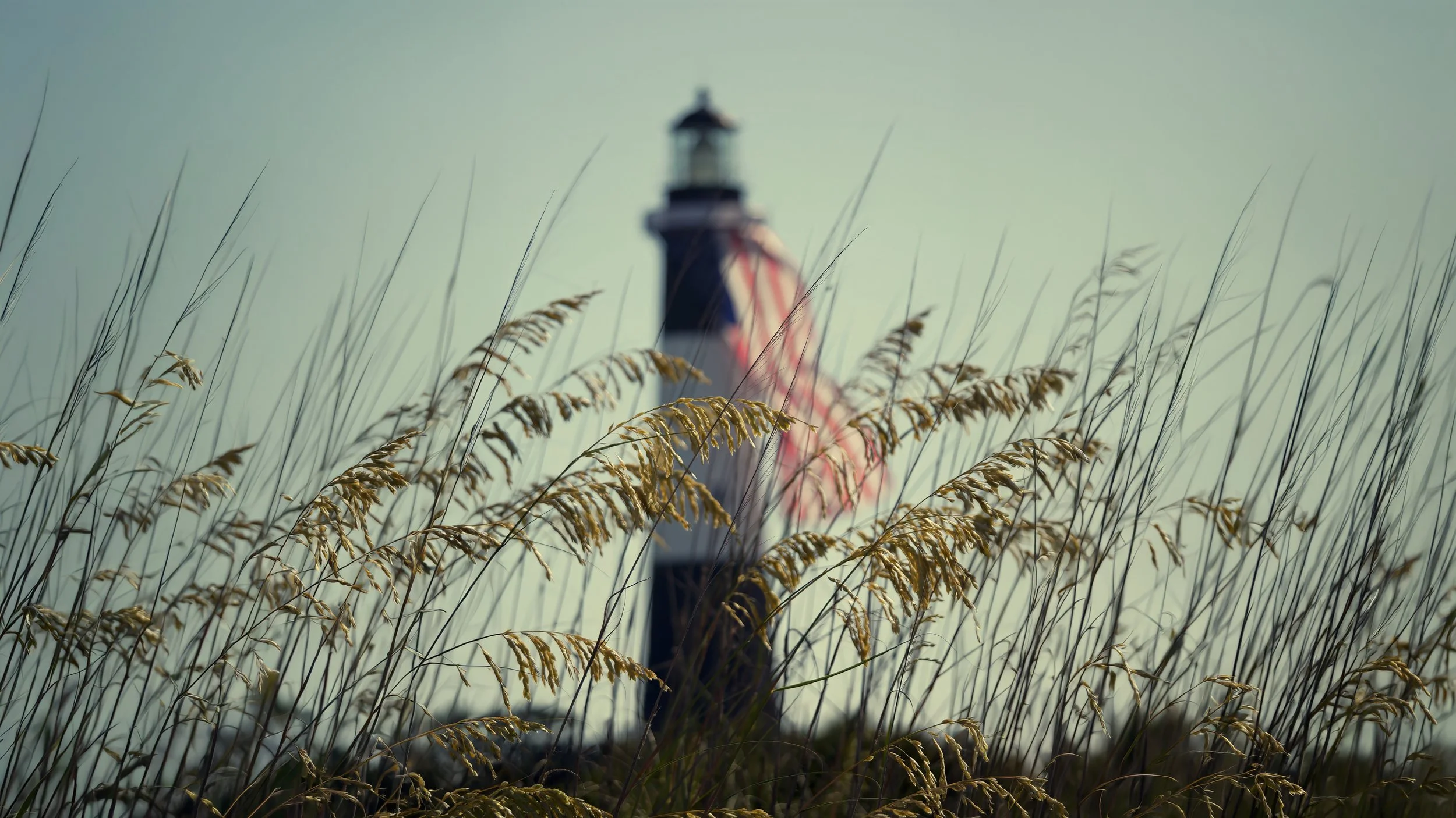 Sea grass sways beneath an American flag draped from the Tybee Island Lighthouse during Fourth of July weekend on Tybee Island, Georgia.