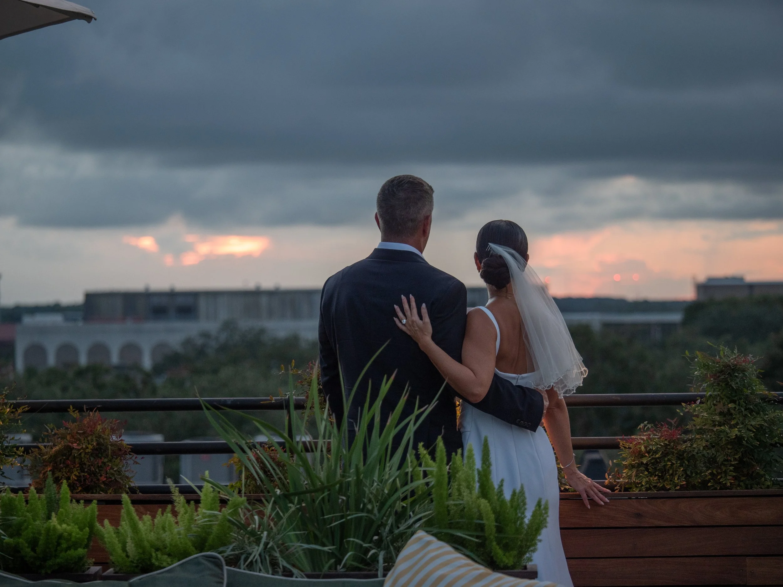 Bride and groom standing together as they watch the evening sky from a Savannah rooftop