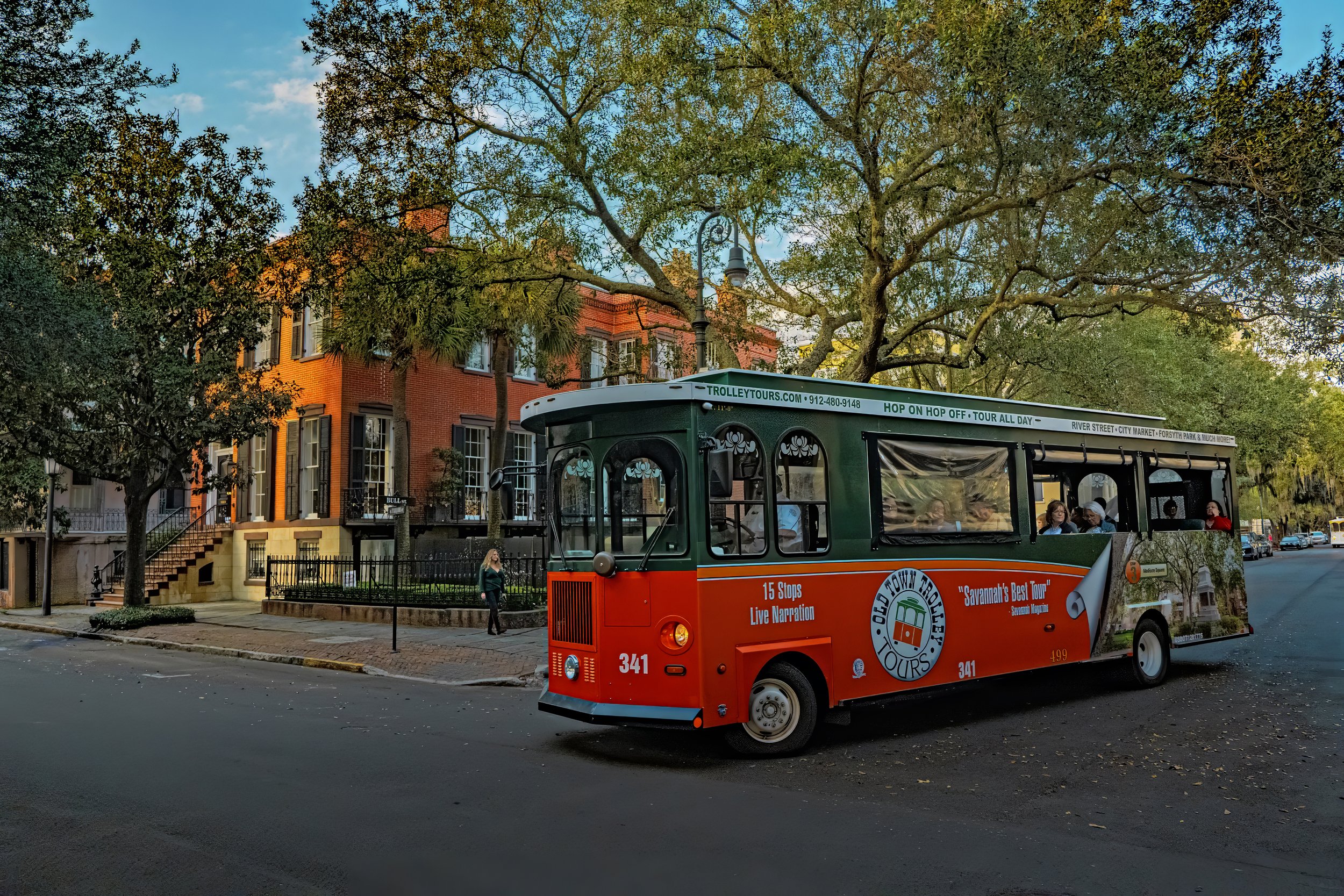 Savannah trolley tour carrying visitors through the historic district with views of historic buildings and streets in Savannah Georgia