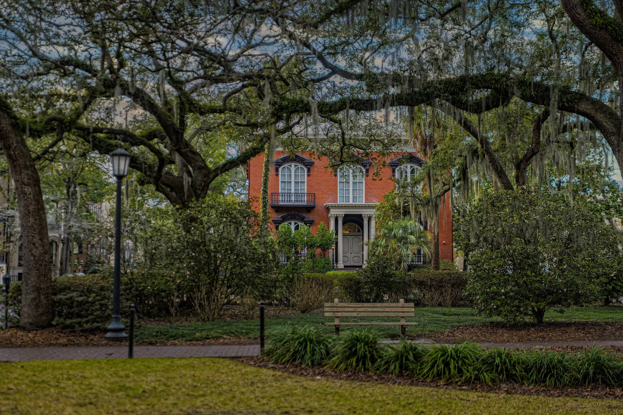 The Mercer House viewed through live oak trees draped with Spanish moss on a historic square in Savannah Georgia