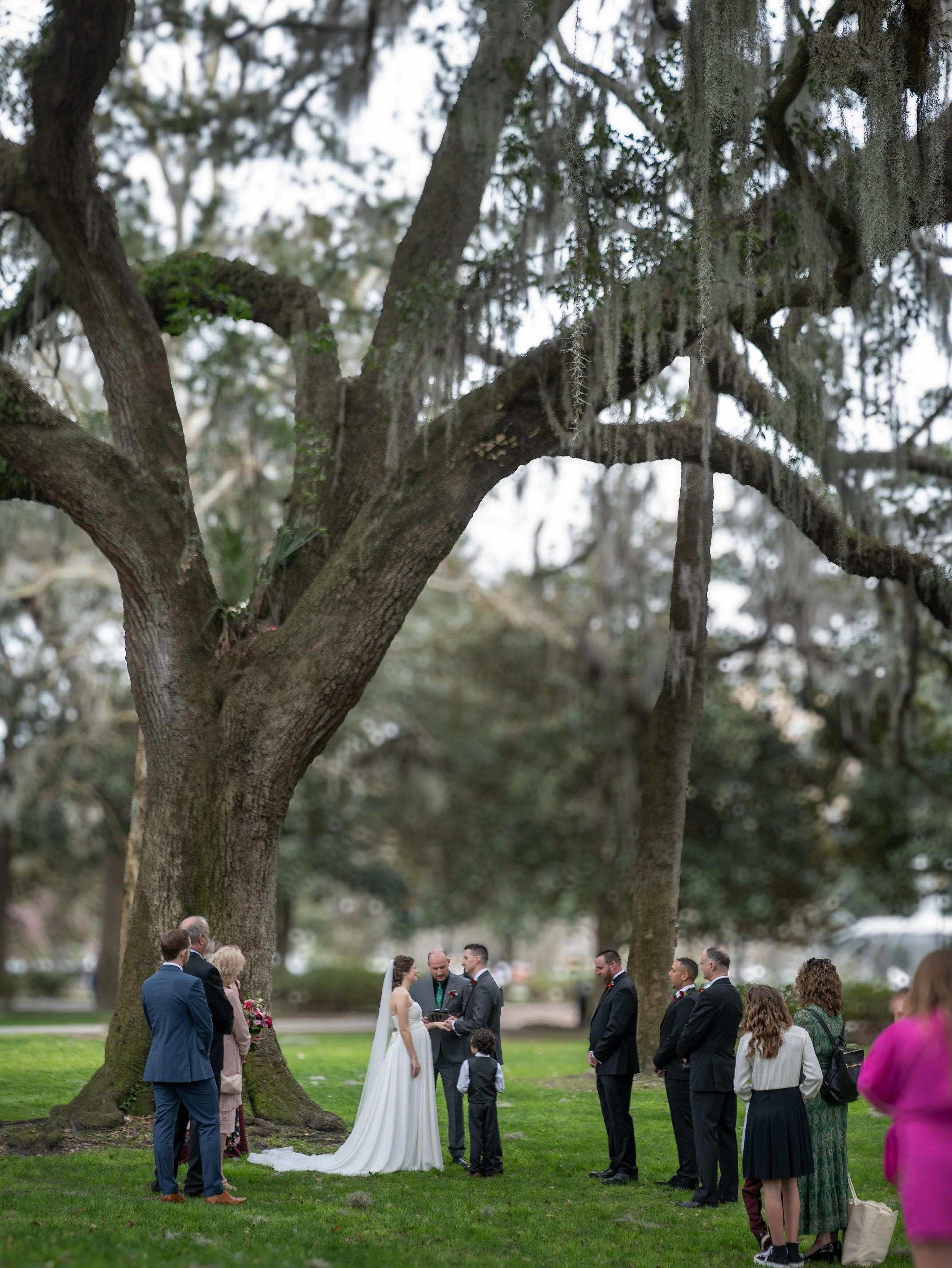 Bride and groom exchange vows beneath the live oak trees during an intimate elopement ceremony in Forsyth Park Savannah Georgia.