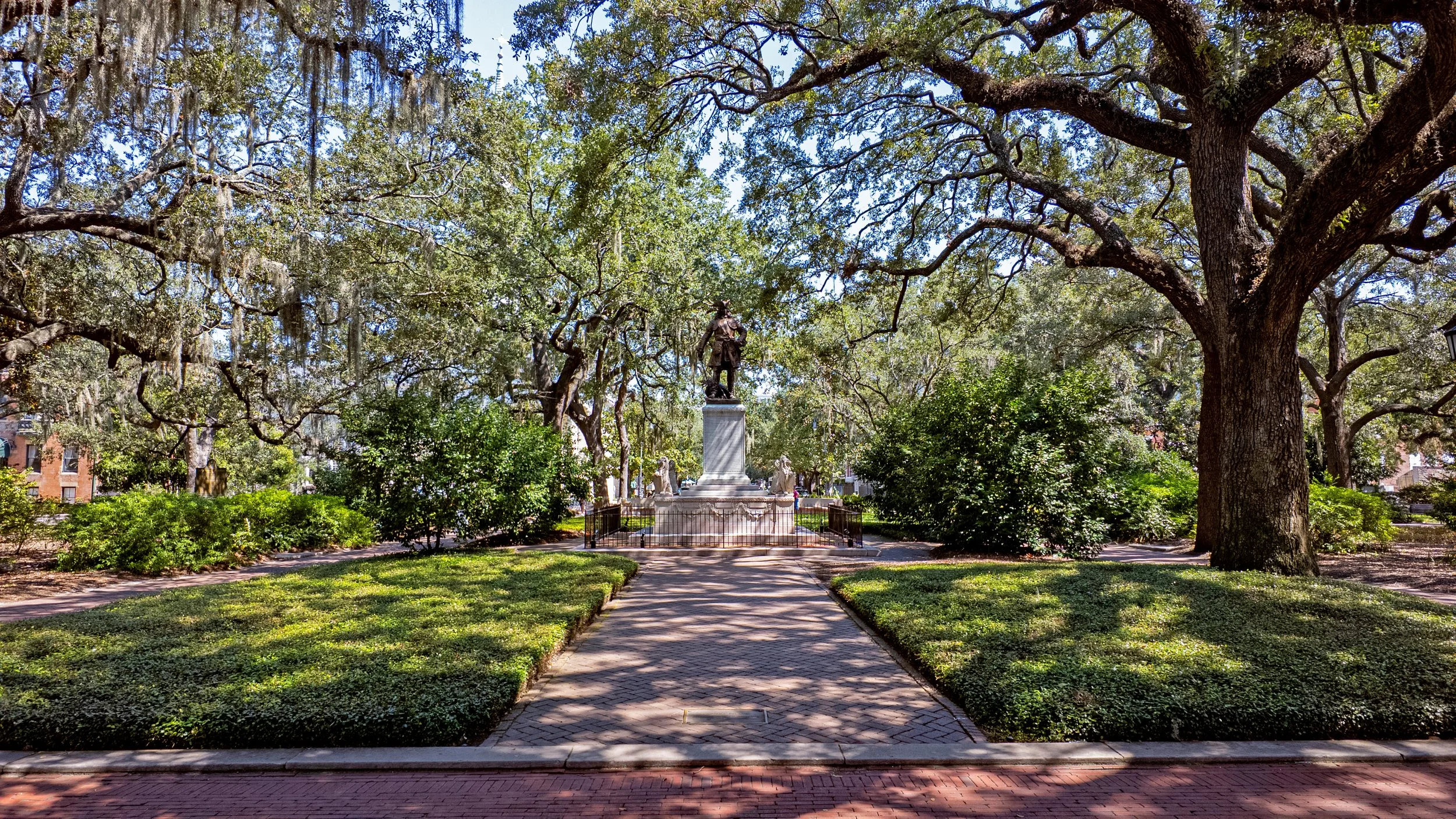 Brick walkway leading toward the Oglethorpe monument beneath live oaks and Spanish moss in Chippewa Square.