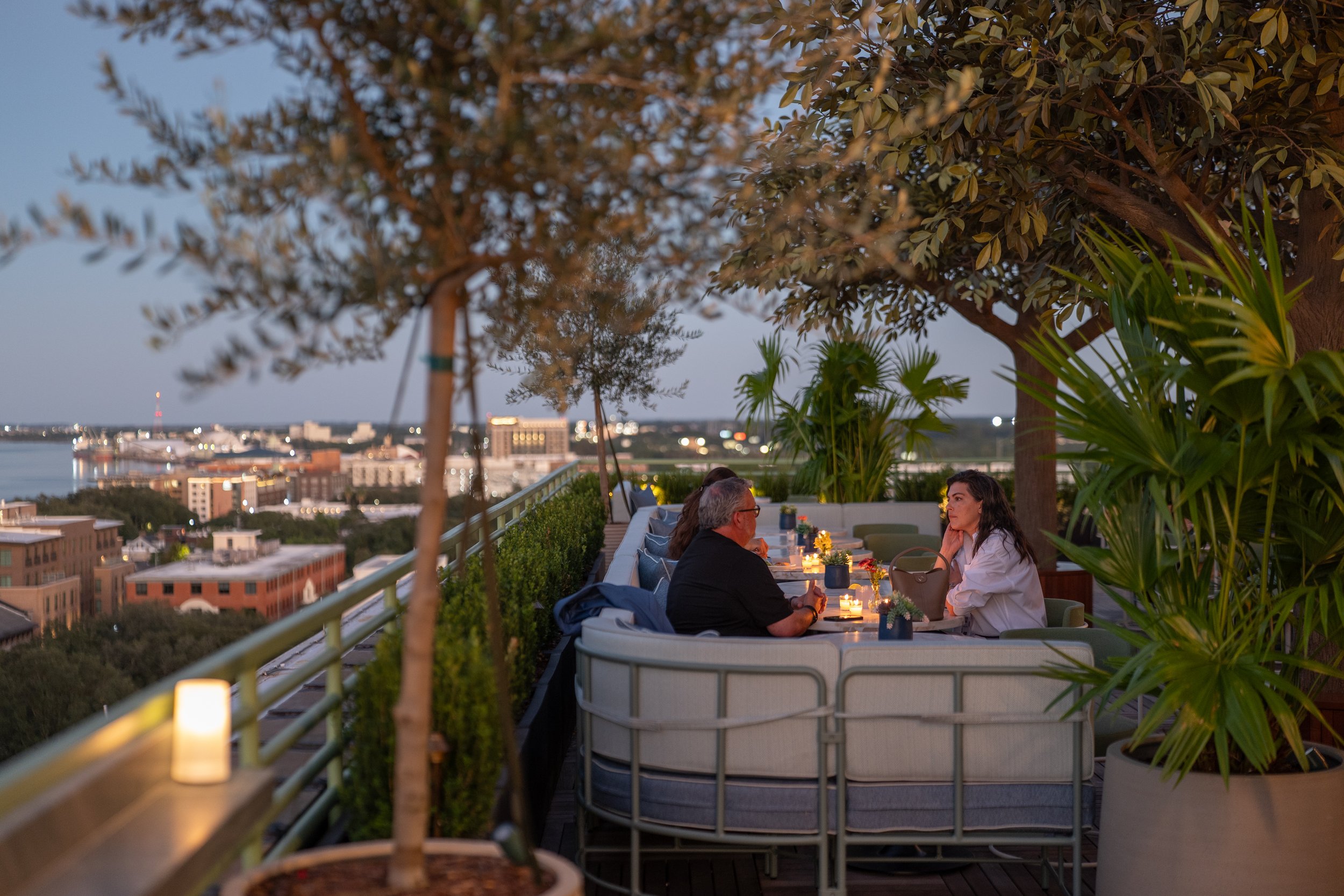 Guests relaxing on rooftop lounge seating overlooking downtown Savannah at Recess Hotel & Club.