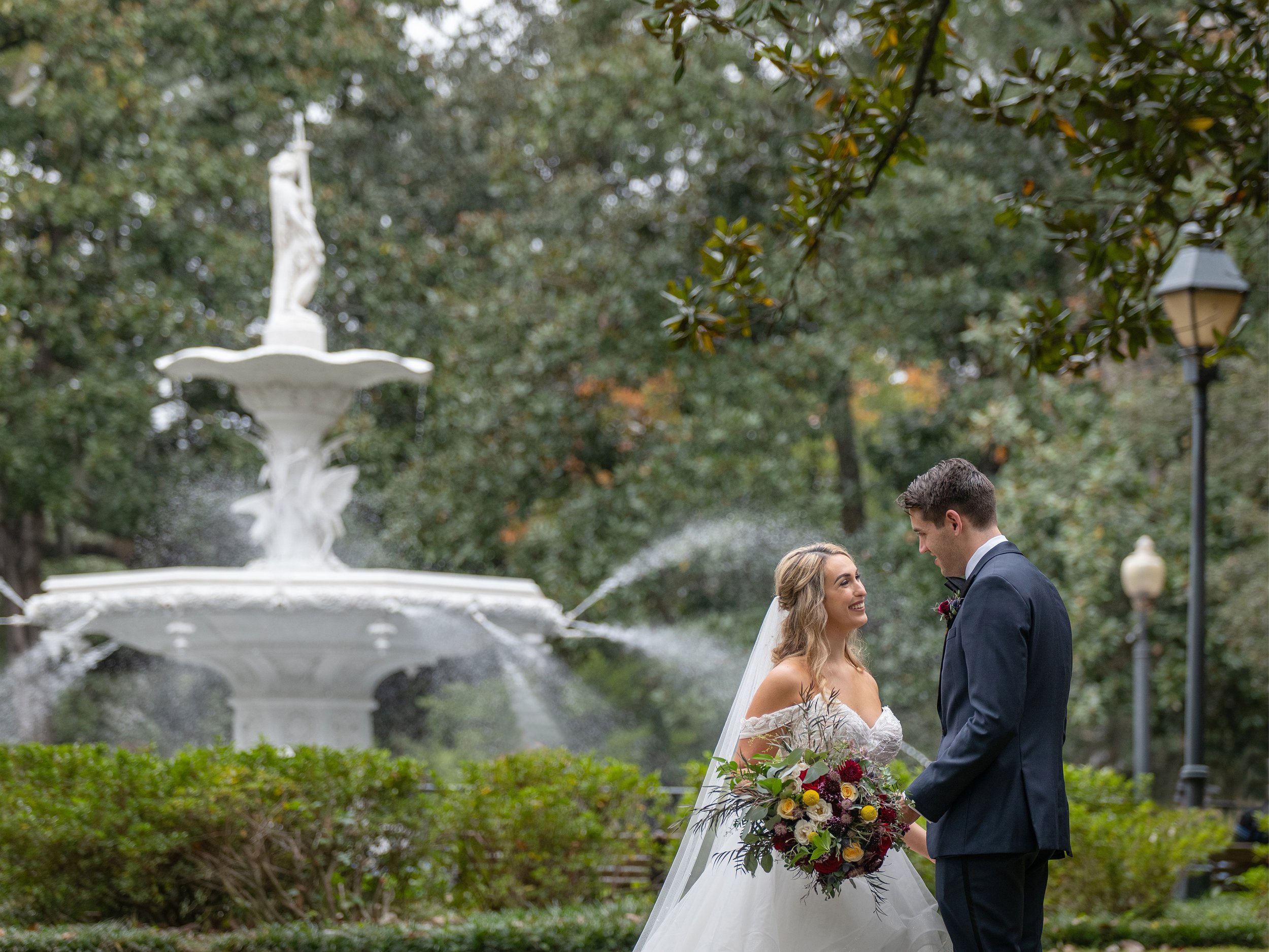 Bride and groom share a romantic moment beside the Forsyth Park Fountain during their Savannah wedding.