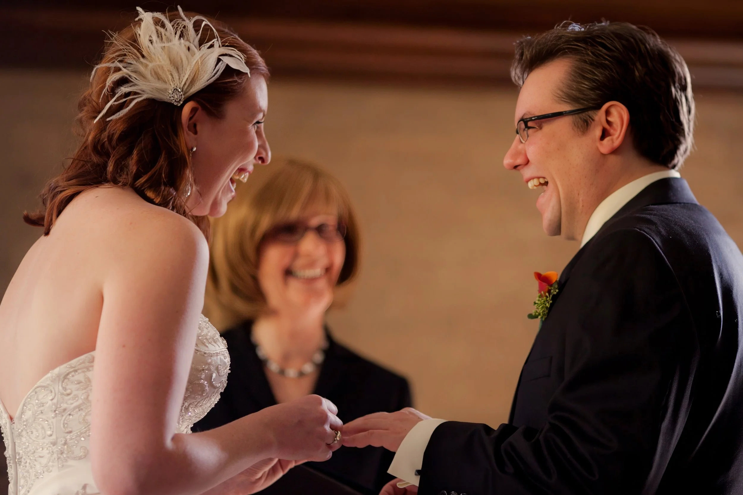Bride and groom laugh together while exchanging rings during their intimate wedding ceremony.