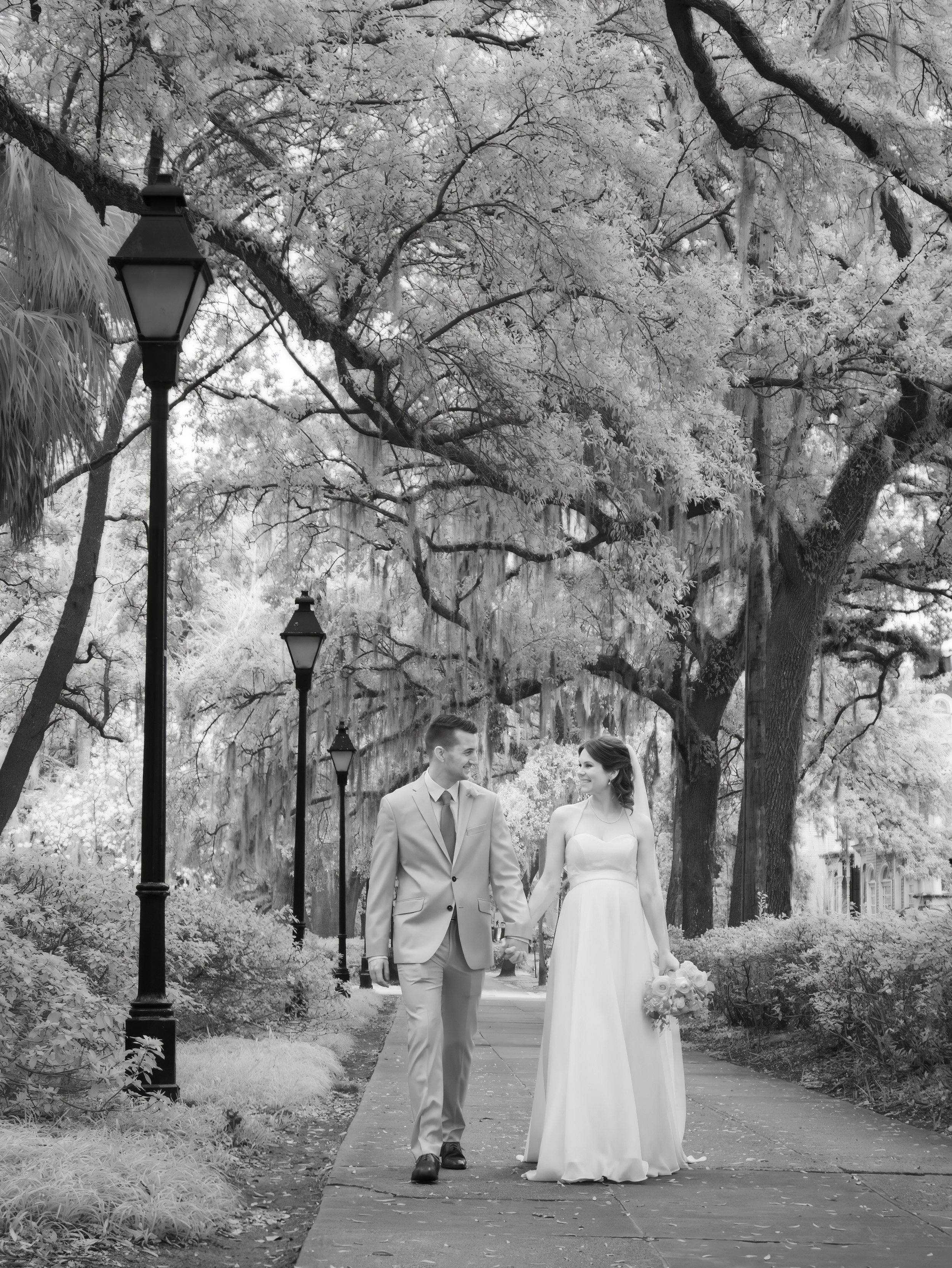 Tim and Daniella walk hand in hand through Savannah in a fine art infrared black and white wedding photograph.