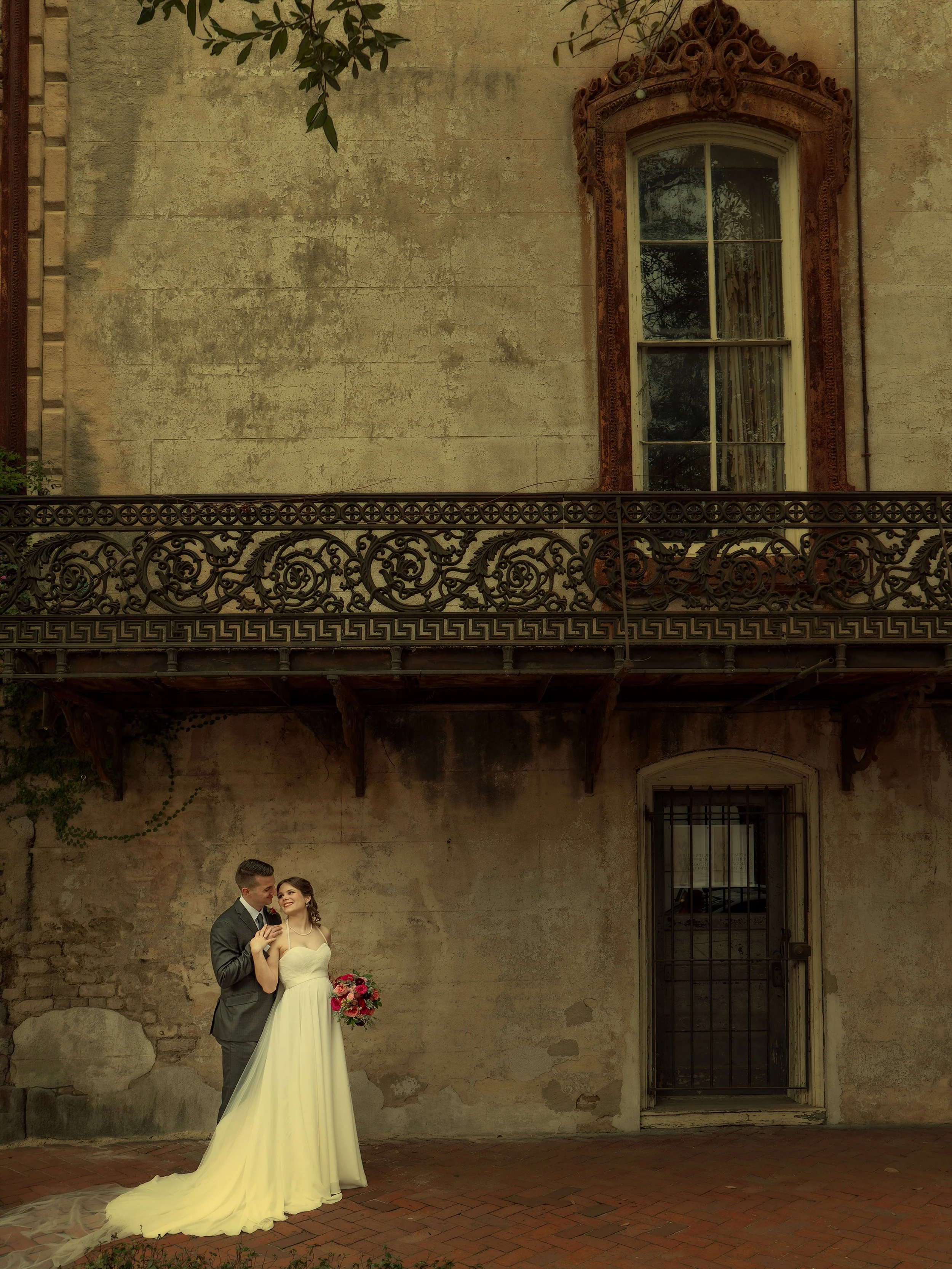 Tim and Daniella pose beside the weathered facade of a historic Savannah mansion during their micro wedding portrait session.