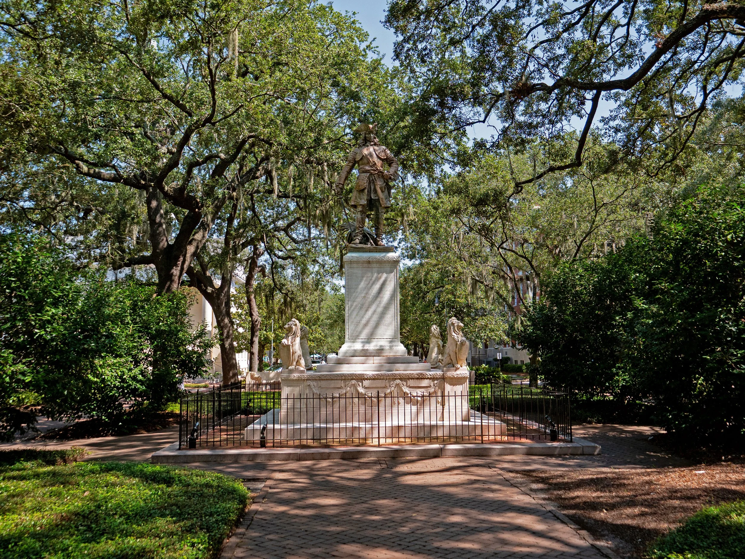 Bronze statue of James Oglethorpe above a tall stone pedestal and sculpted lions in Chippewa Square.