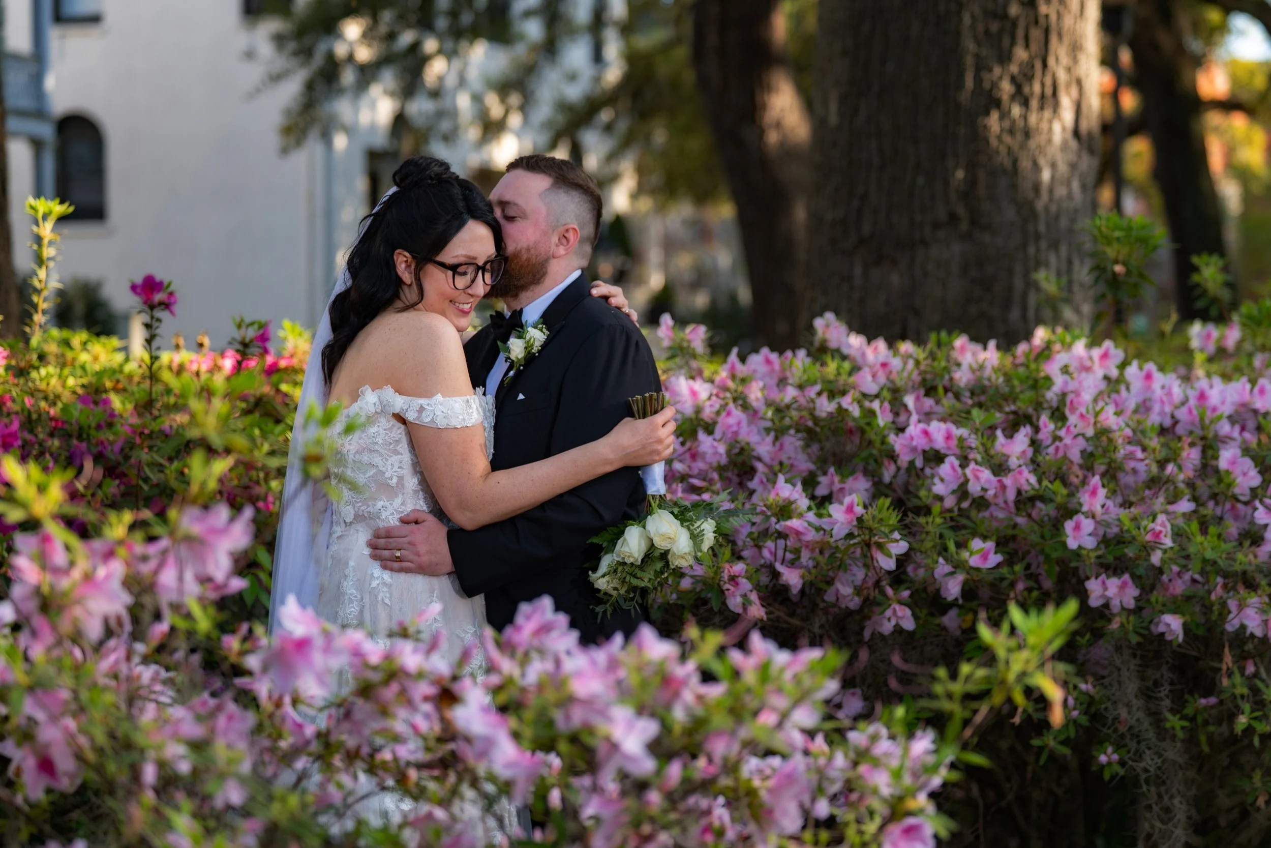 Wedding couple walking through Forsyth Park surrounded by blooming azaleas in Savannah Georgia photographed by Maring Visuals