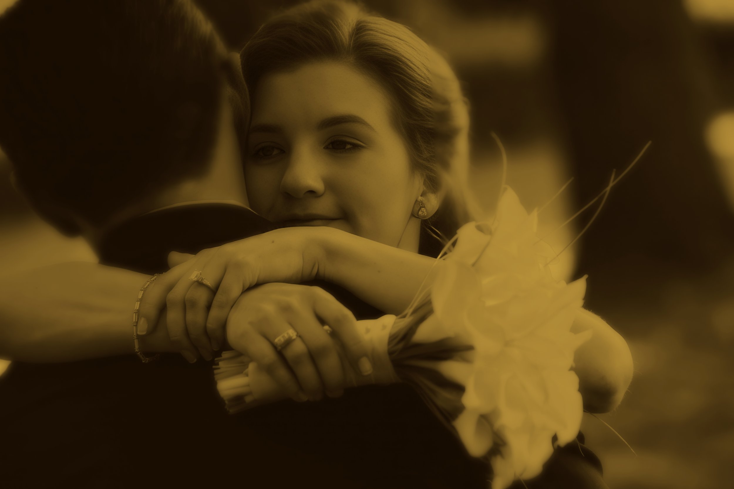 Fine art split tone portrait of a bride embracing her husband while holding her wedding bouquet.