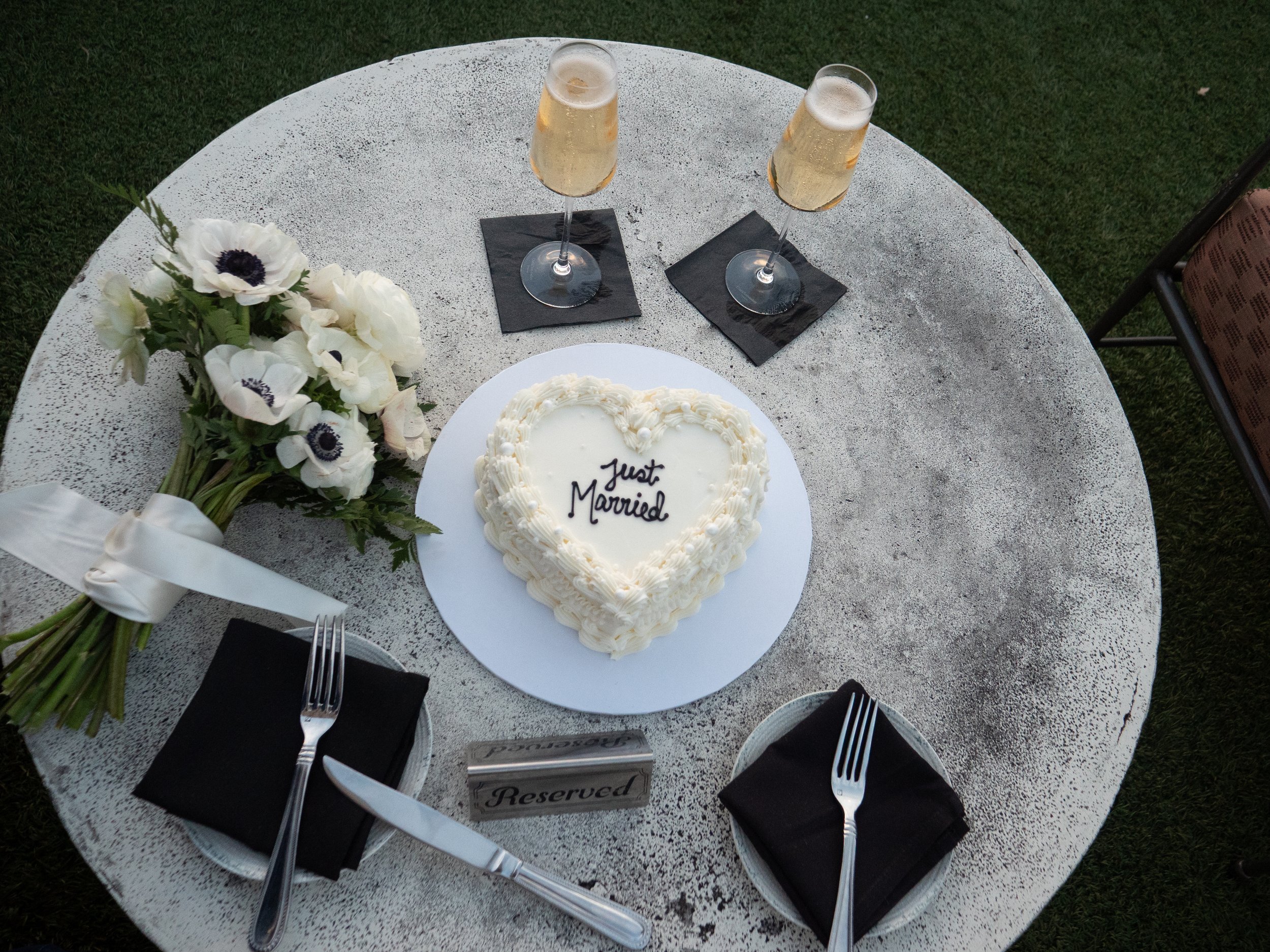 Small wedding cake, champagne, white bouquet, and table setting on the Peregrin rooftop