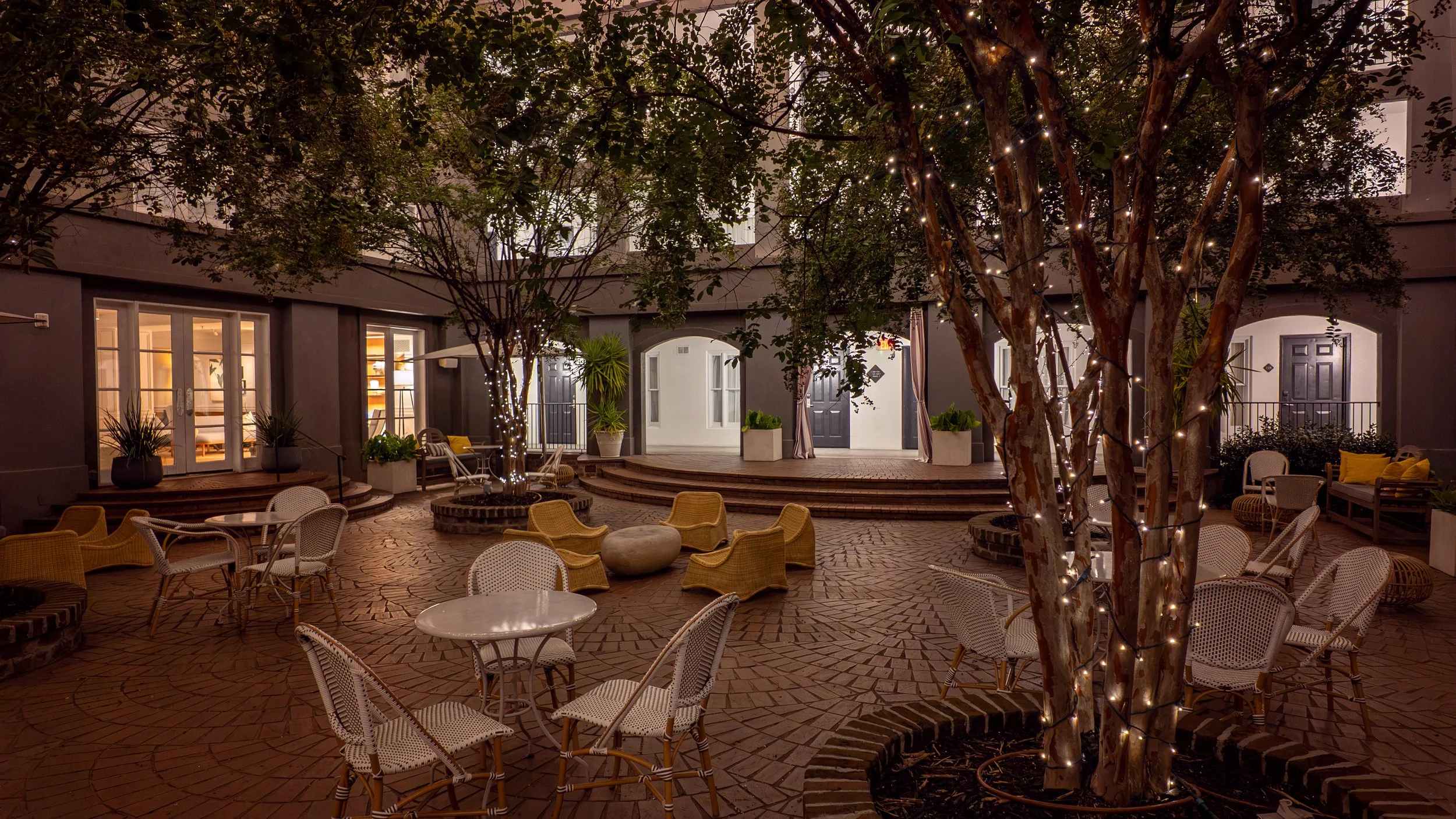 The illuminated courtyard at Kimpton Brice glows beneath Edison lights in Savannah at night.