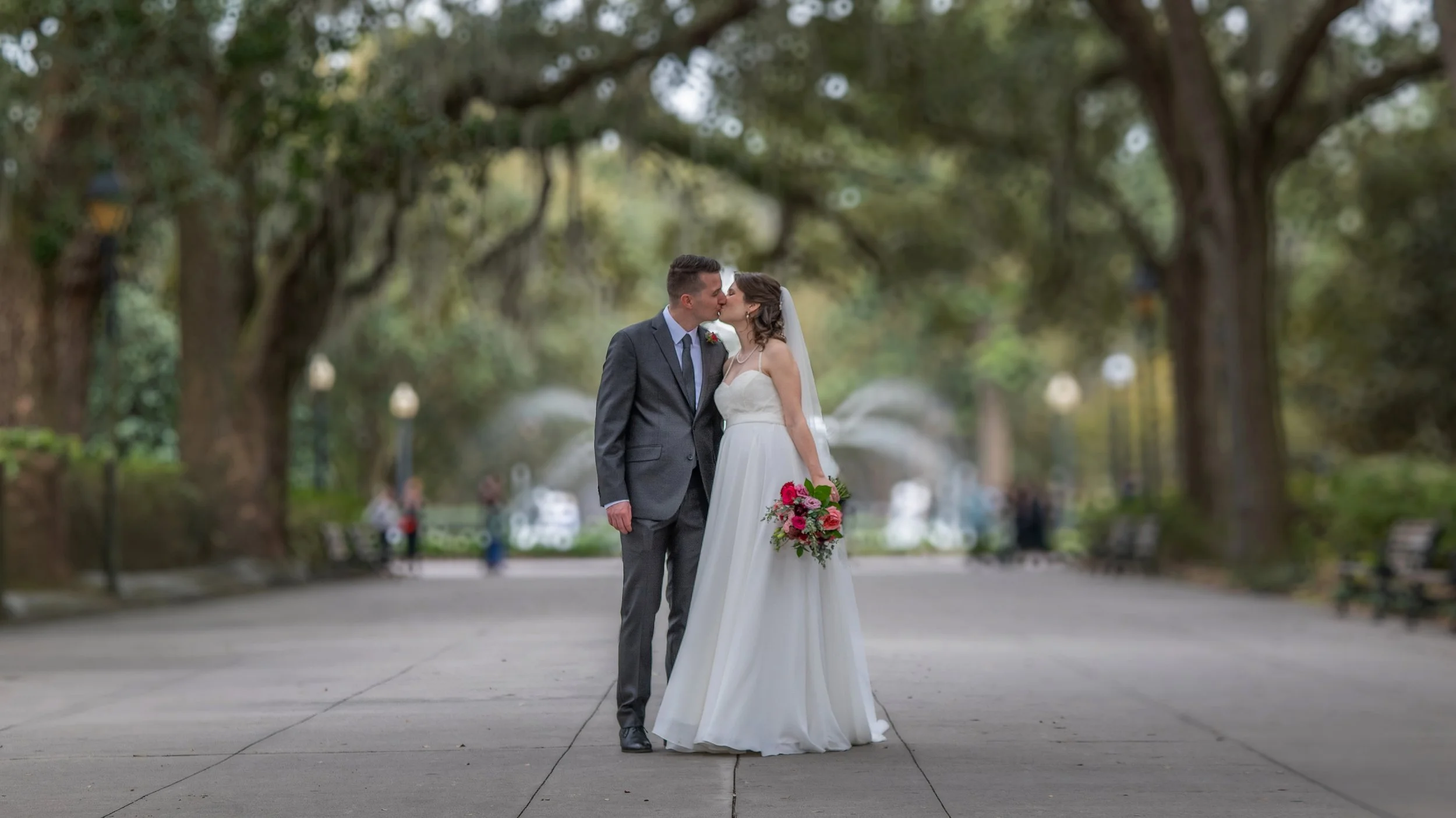Bride and groom kiss on the Forsyth Park promenade near the iconic fountain during their Savannah elopement.