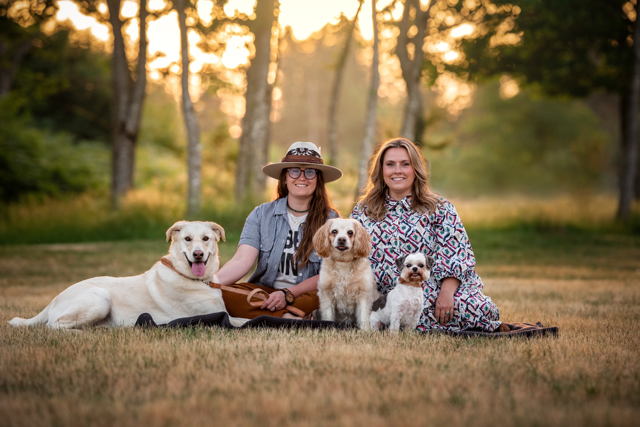 Two women, a married lesbian couple, sit in a field in North Bend with their three dogs
