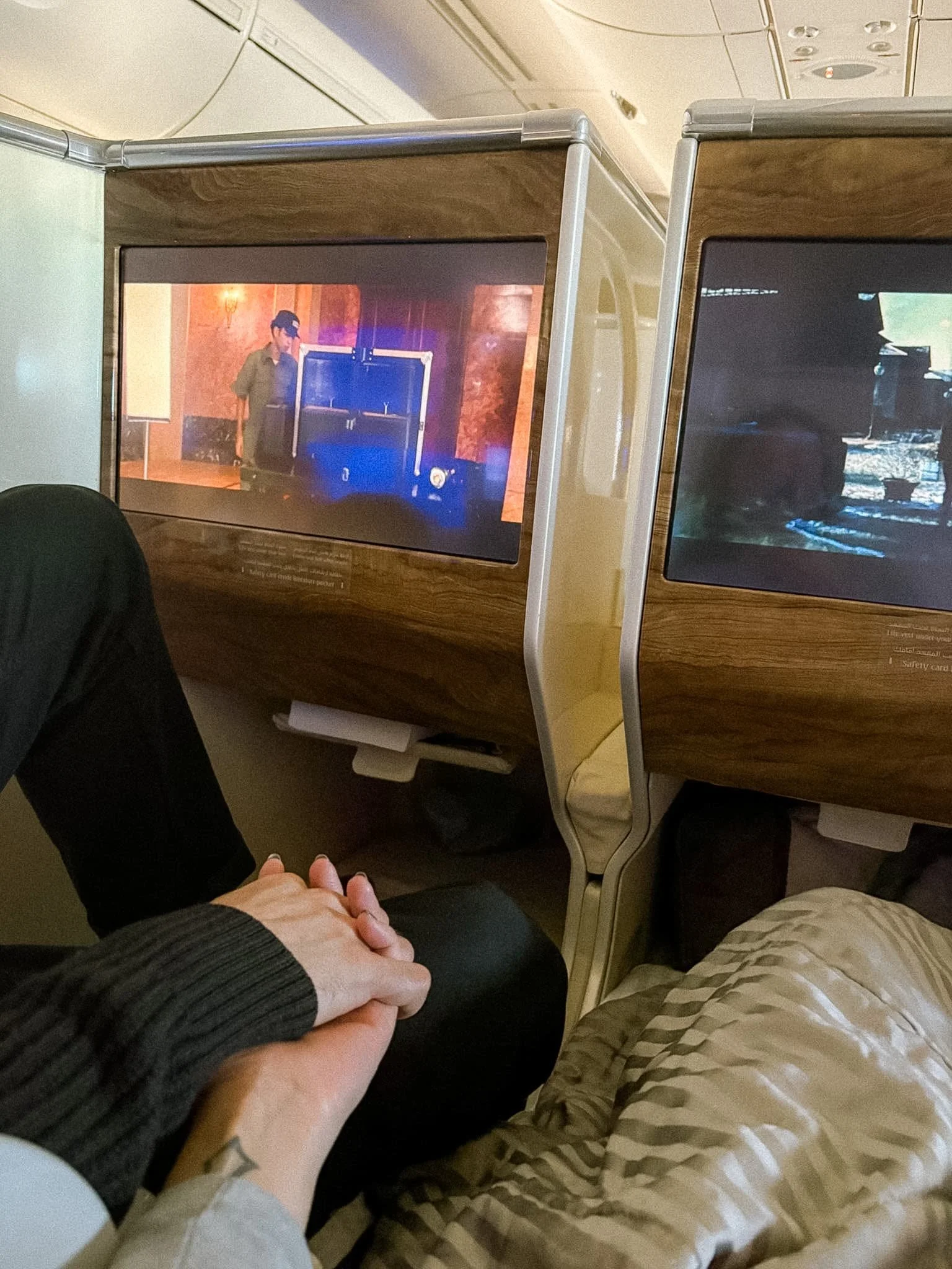 Couple holding hands in Emirates Business Class seats on the A380