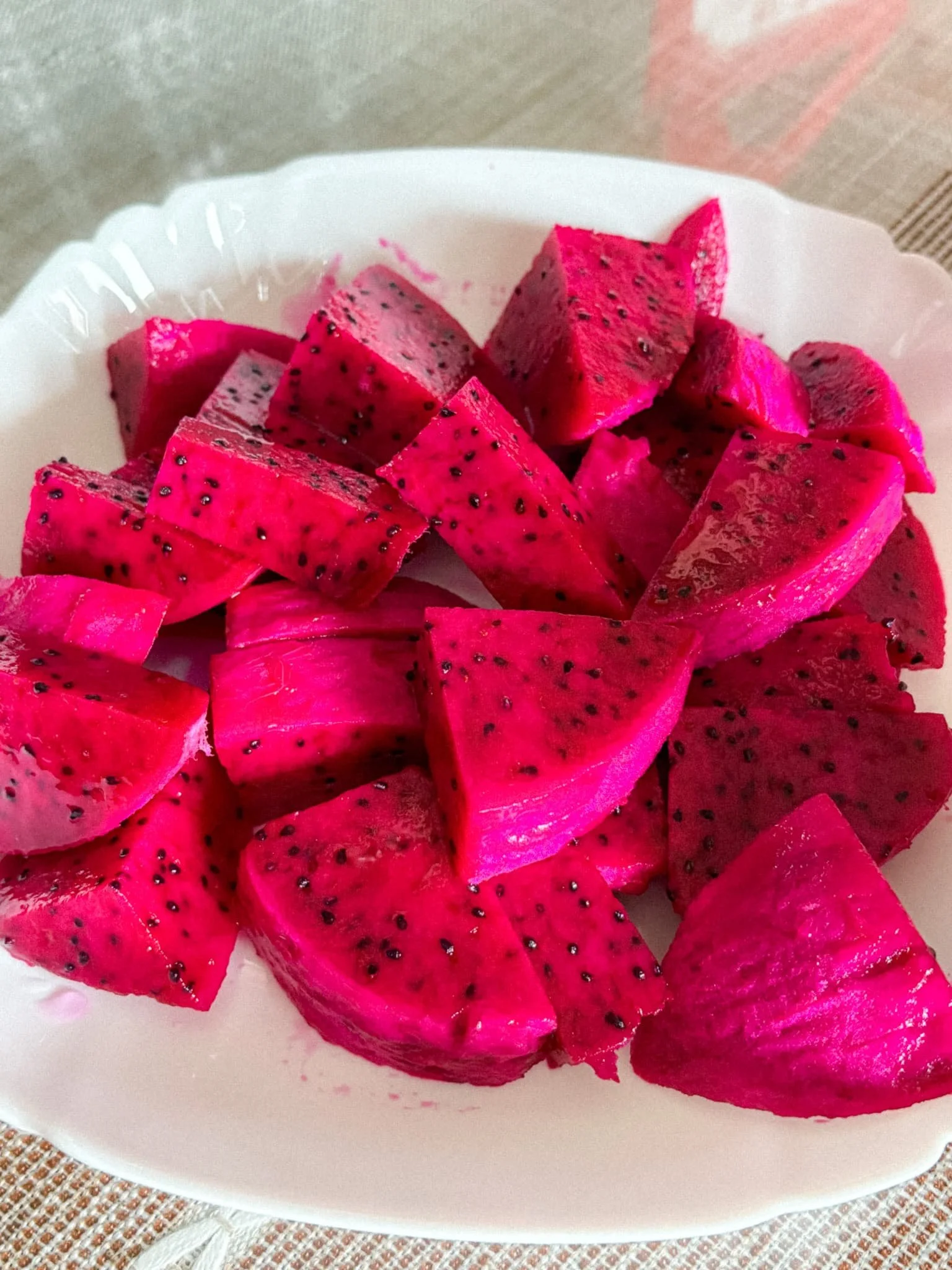 Sliced red-fleshed dragonfruit with black seeds on a white plate in Taiwan