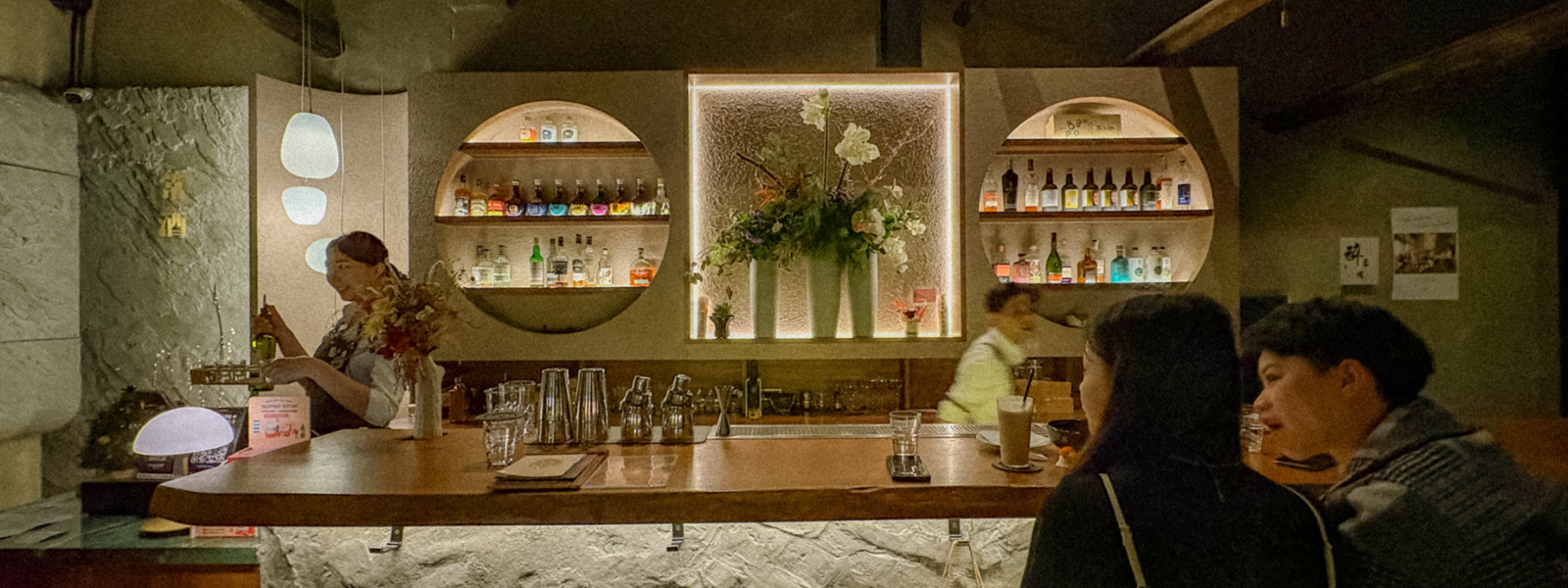 Bar Often Tainan cocktail bar interior with glowing circular liquor displays and floral centerpiece
