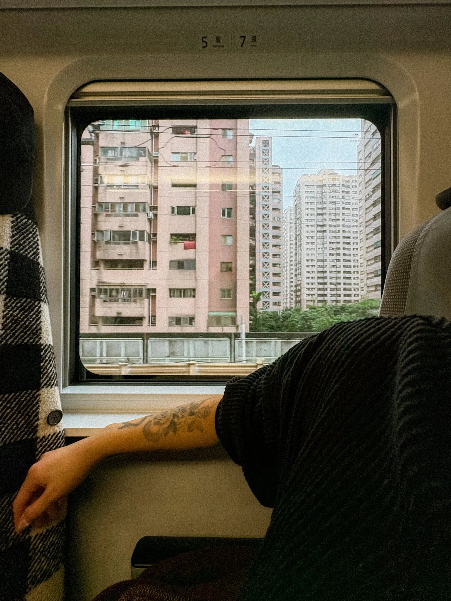 View from Taiwan Railway train window with coat hook and passing city, real TRA onboard travel experience