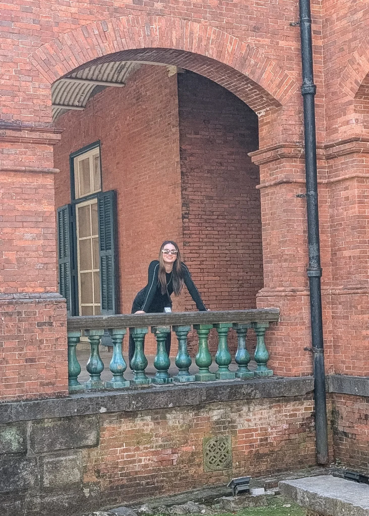 Melinda leaning on a green balustrade at the red brick British Consular Residence in Tamsui