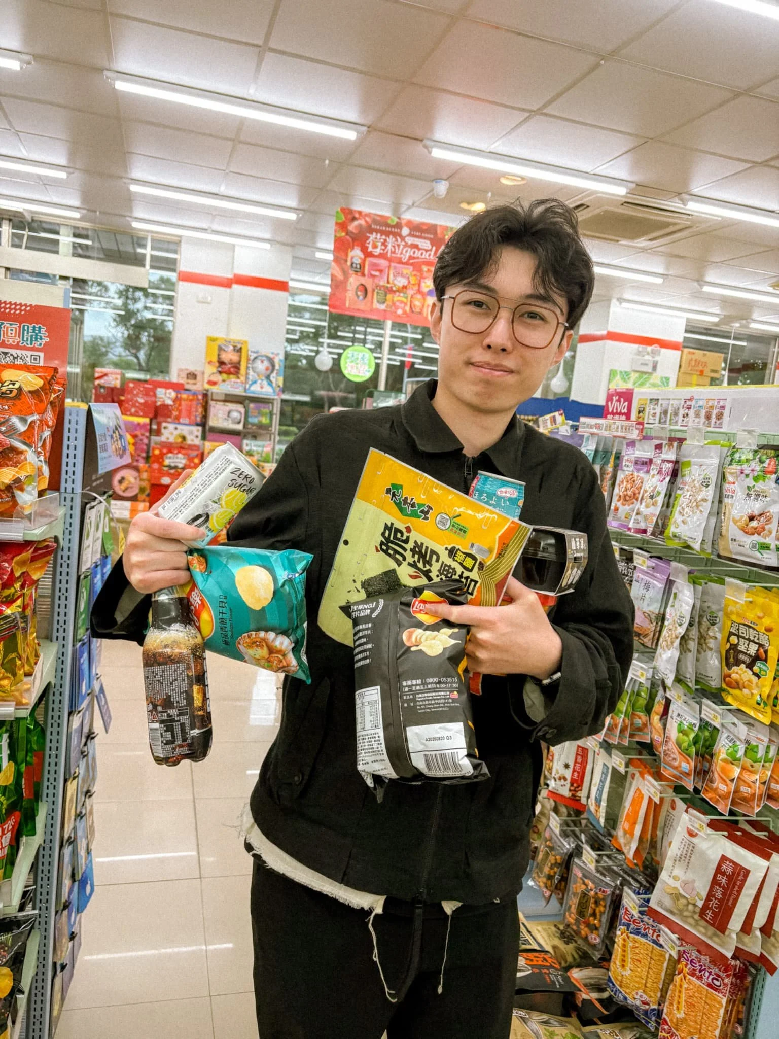 Person holding assorted Taiwanese snacks and chips inside a Taiwan convenience store aisle