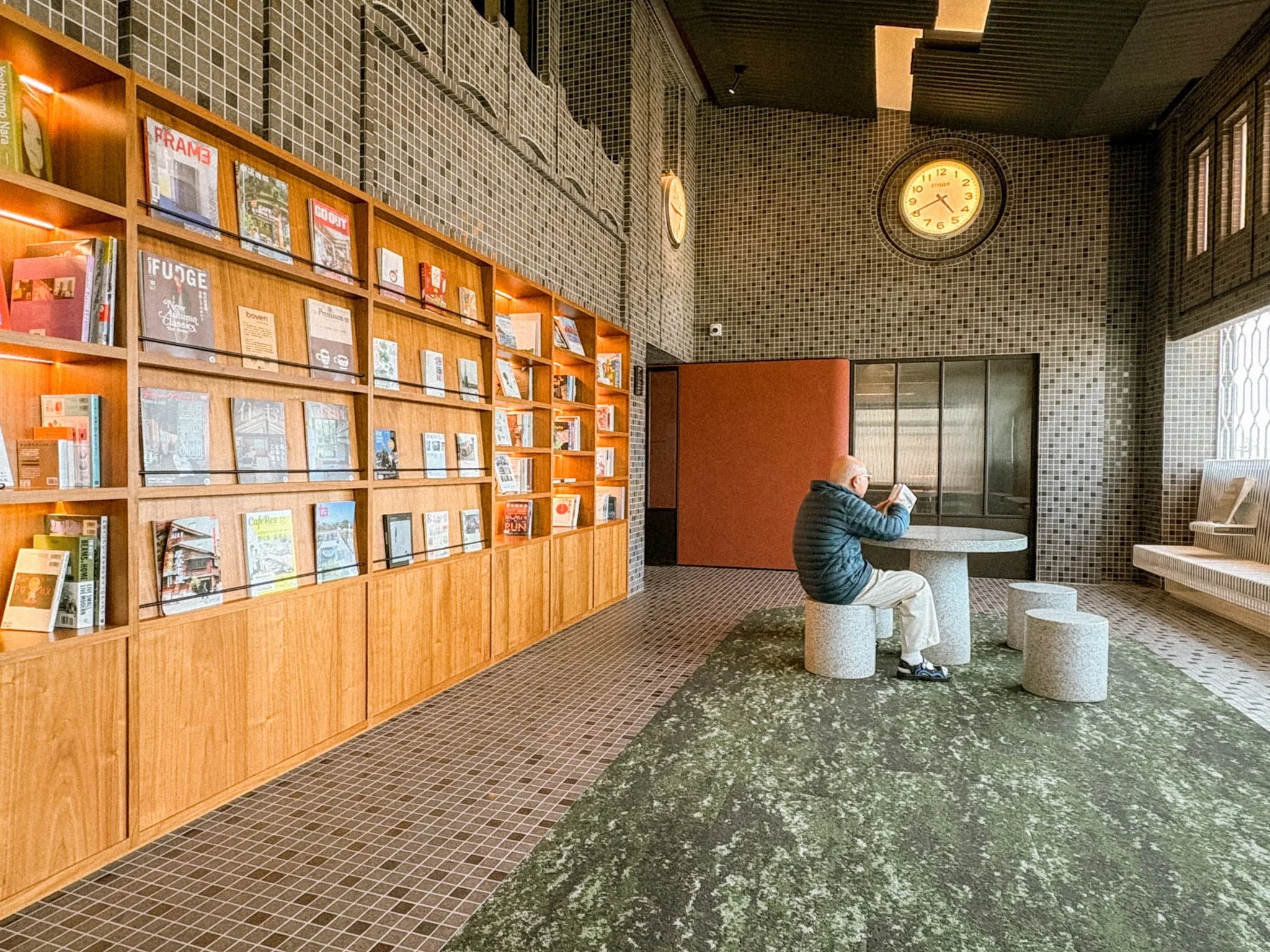 Guest reading in Provintia Hotel Tainan's retro library lounge beside a vintage clock