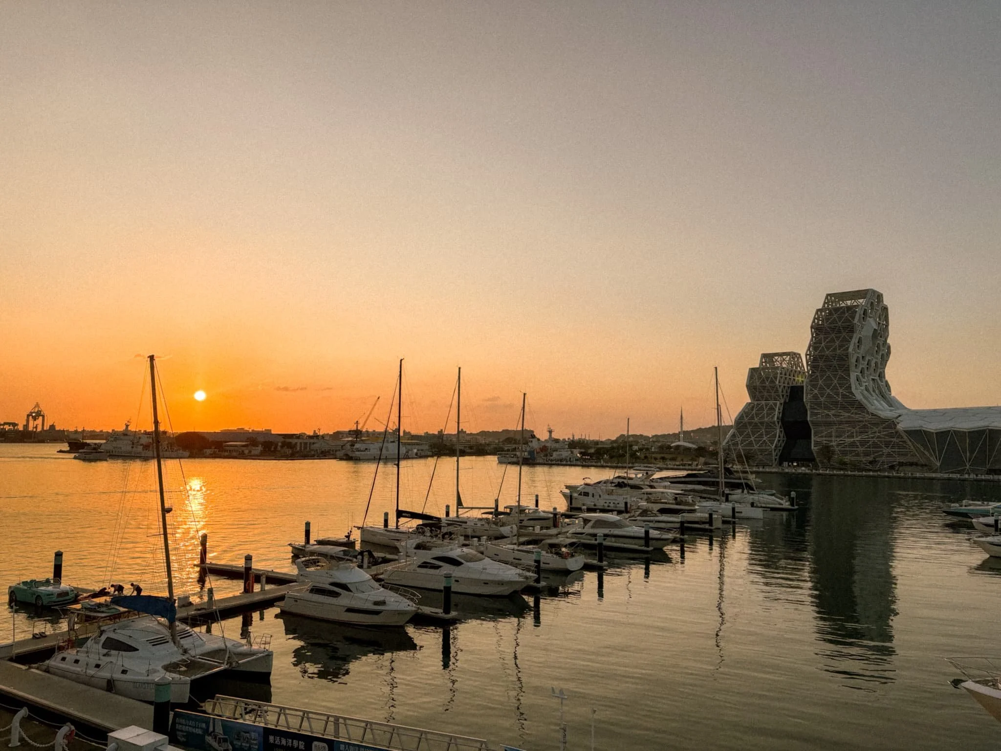 Sunset over Glory Pier marina in Kaohsiung Taiwan with sailboats and National Kaohsiung Center for the Arts