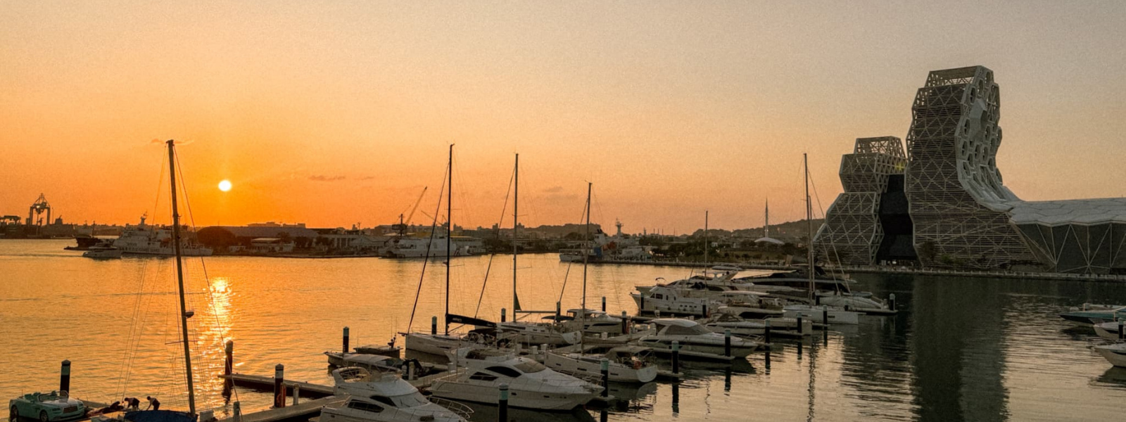 Sunset over Glory Pier marina in Kaohsiung Taiwan with sailboats and National Kaohsiung Center for the Arts