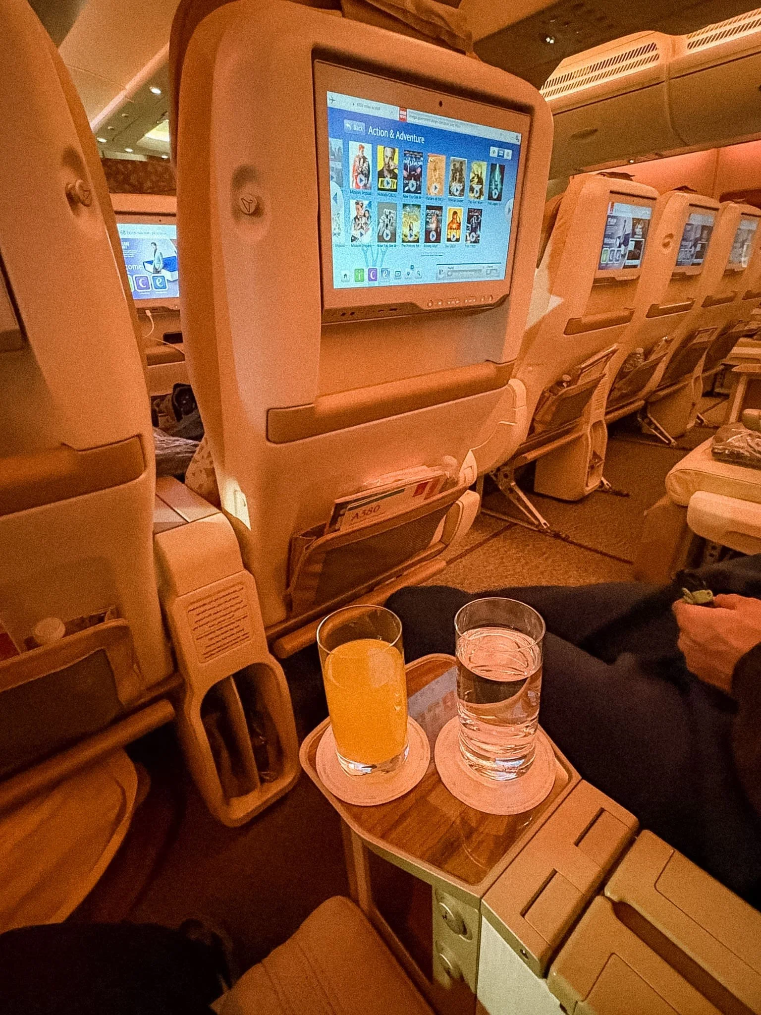 Emirates Premium Economy welcome drinks served in glass cups with apple juice and water on wooden tray