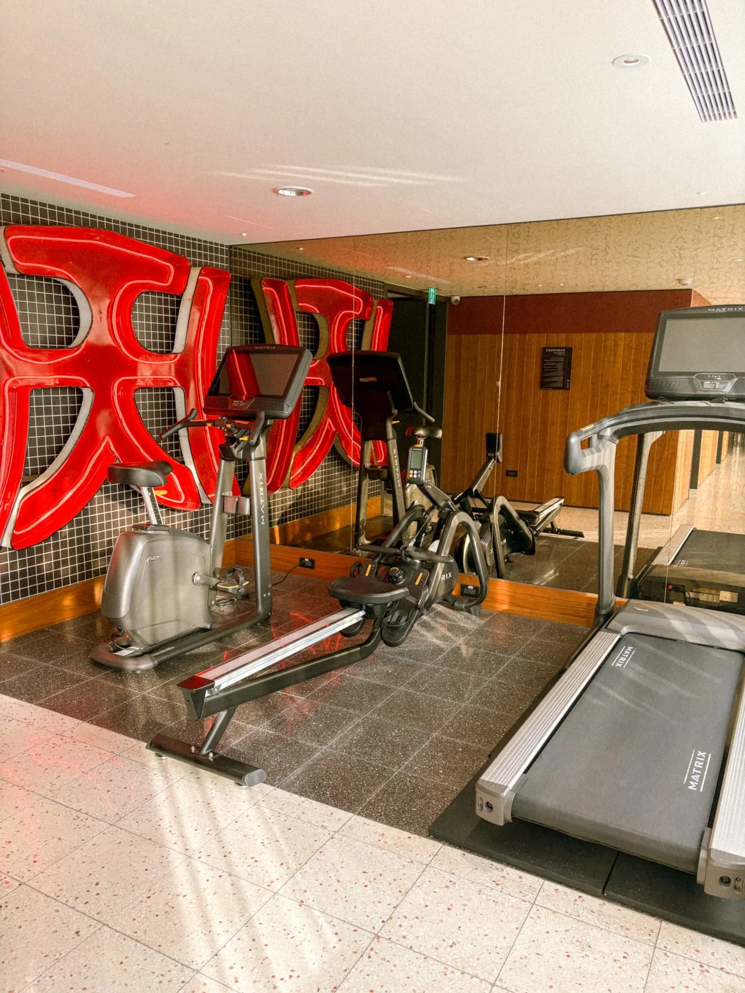Small fitness room at Provintia Hotel Tainan with two treadmills and retro red wall art