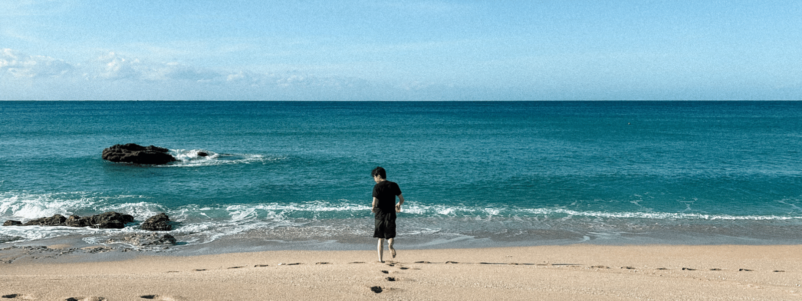 Person walking barefoot on white sand toward turquoise ocean at Baisha Beach, Kenting Taiwan
