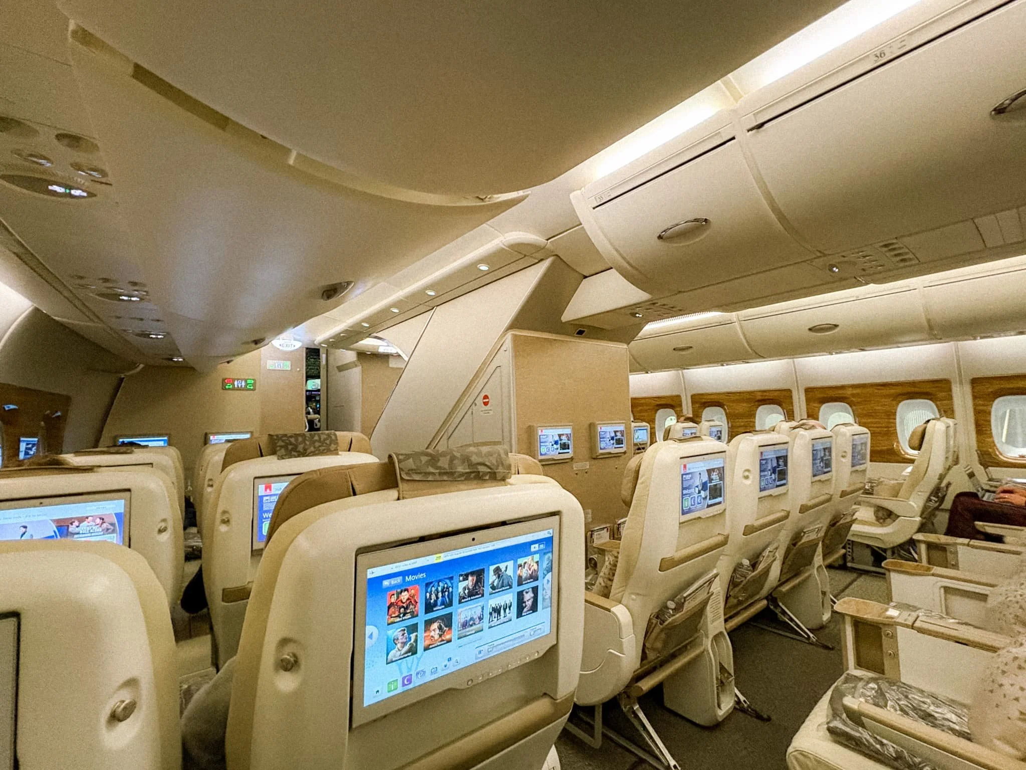 Emirates Premium Economy cabin on the A380 showing 2-4-2 seat configuration with large entertainment screens and high ceilings