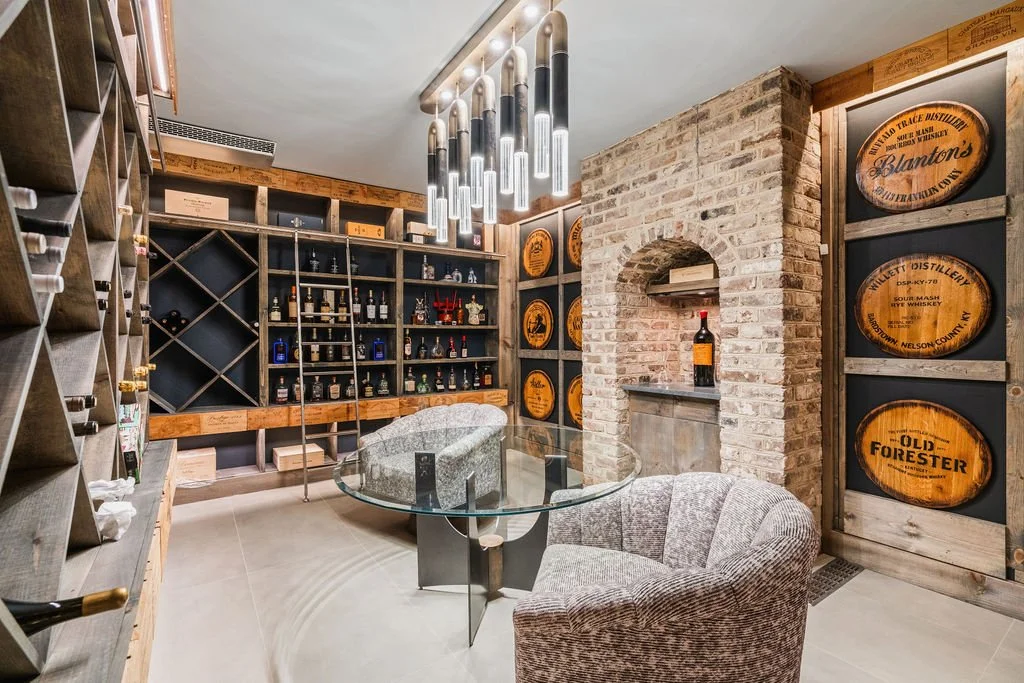 Custom wine/bourbon cellar with built-in bottle storage, reclaimed bourbon barrels, exposed brick, modern lighting and lounge seating.