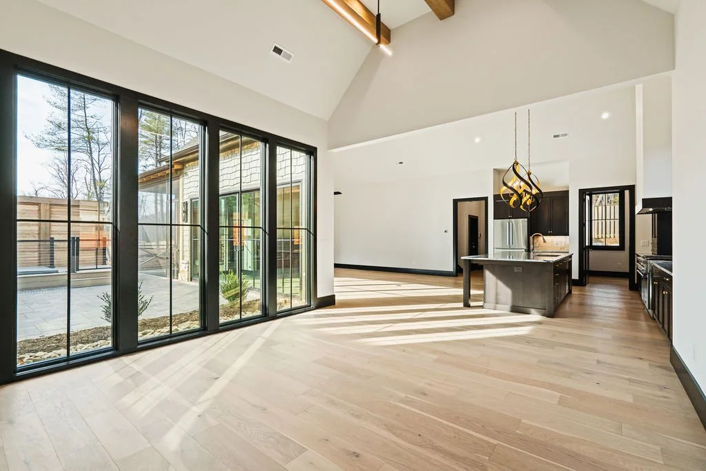 Empty dining room leading to a kitchen and living room with large windows looking into a courtyard.