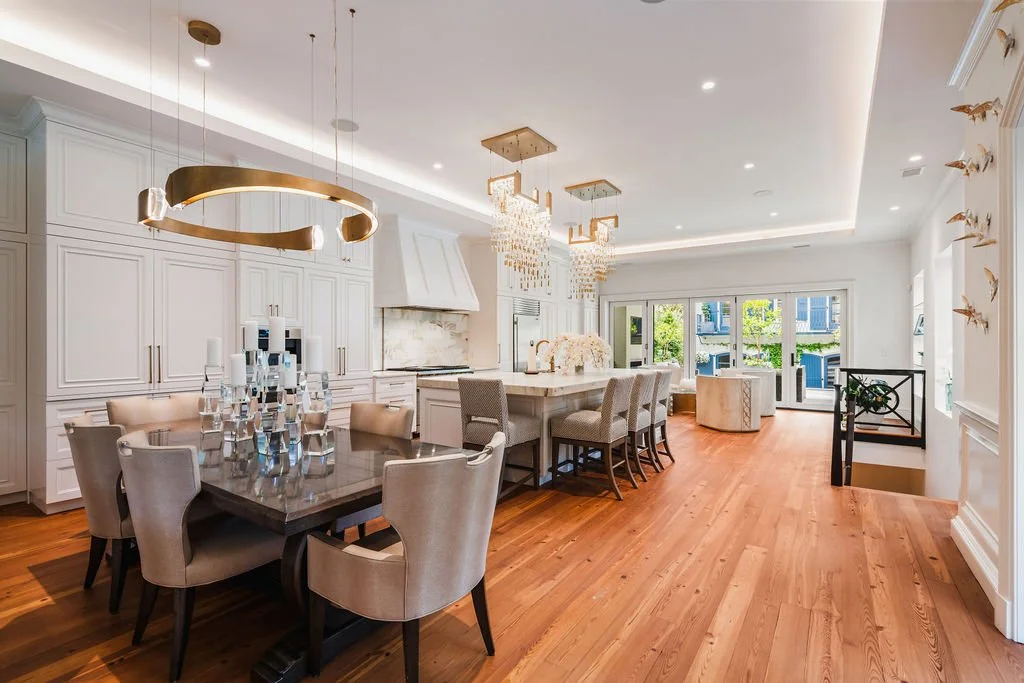 Bright Charleston kitchen and dining room with white custom cabinetry, marble surfaces, crystal lighting and warm hardwood floors.