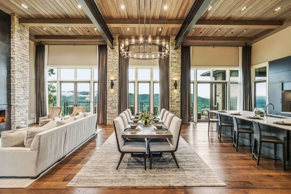 Luxury mountain home near Asheville with a timber ceiling, stone columns, dining area, modern kitchen and panoramic Blue Ridge views.