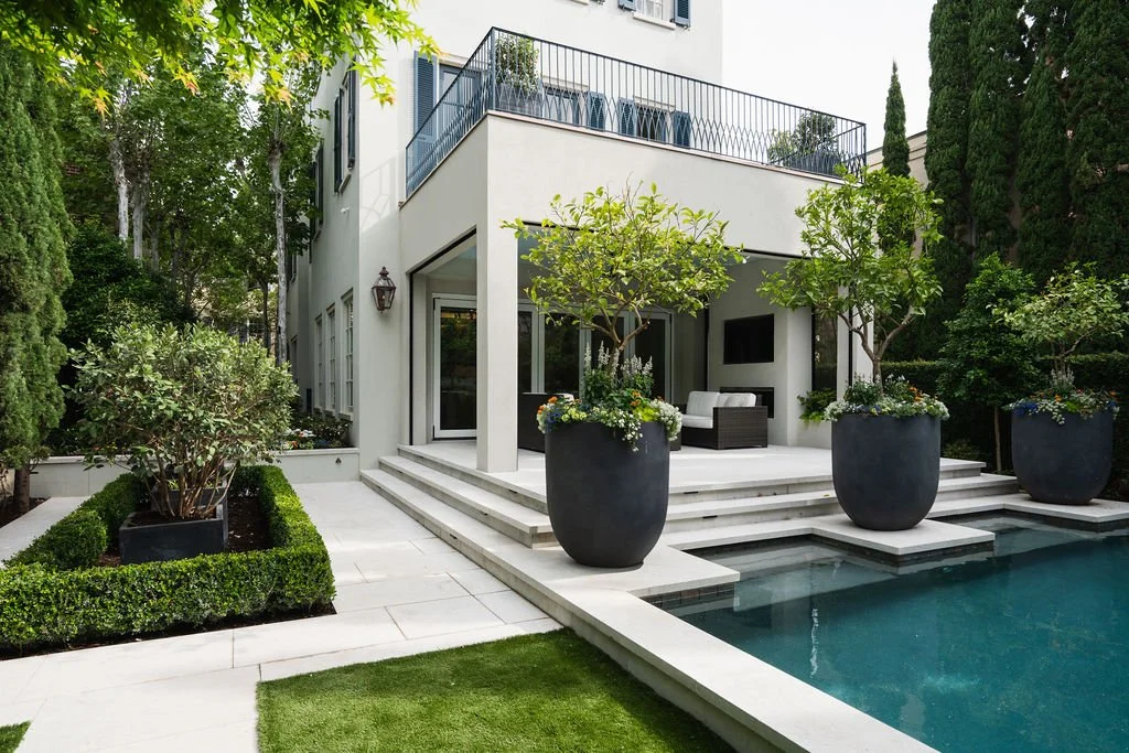 Luxury Charleston courtyard with a modern pool, covered outdoor living area, rooftop terrace, formal landscaping and large planters.
