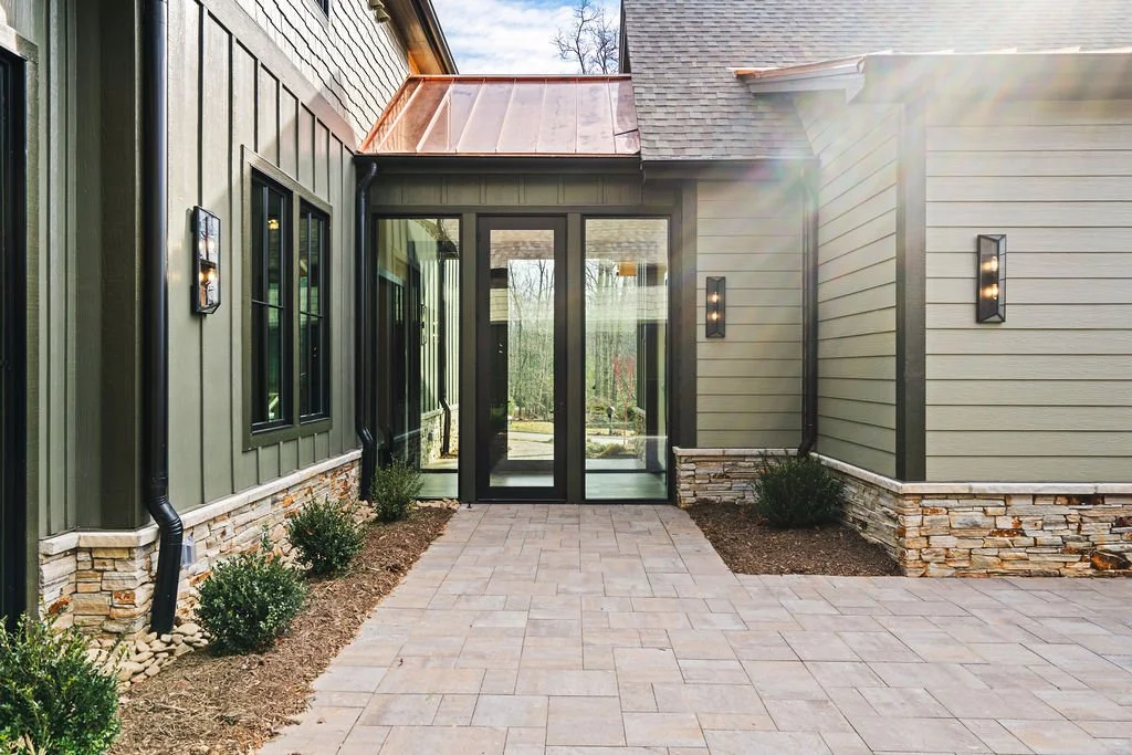 Olive green house exterior with slate floor and sun flare.