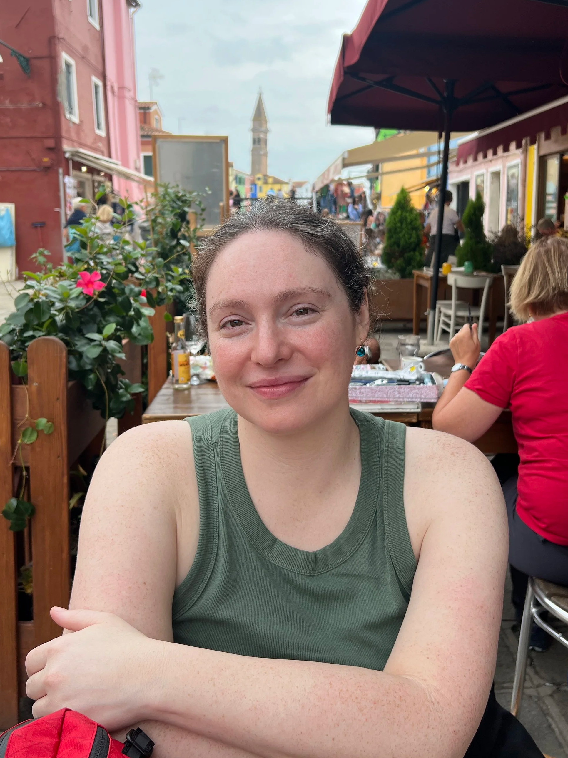 Image of Rachel Diane Gordon, Licensed Therapist in Washington State. Woman smiling wearing a green tank top with her hair up at a cafe.