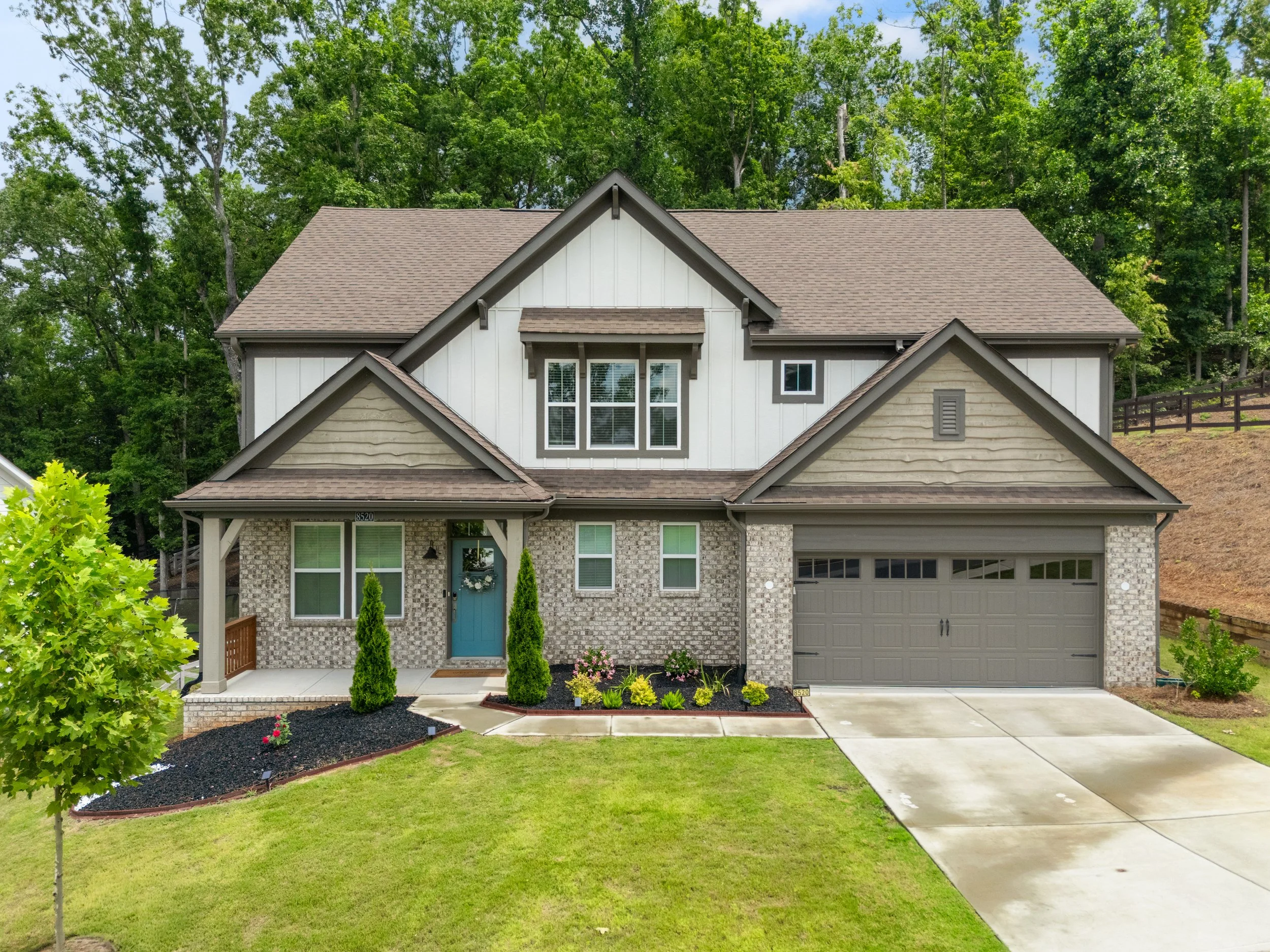"Two-story craftsman home with board and batten siding and a covered entry in Ball Ground Georgia, set on a landscaped lot."