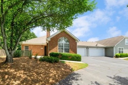 "Brick ranch-style home with attached garage in Duluth Georgia, framed by a mature shade tree in the front yard."