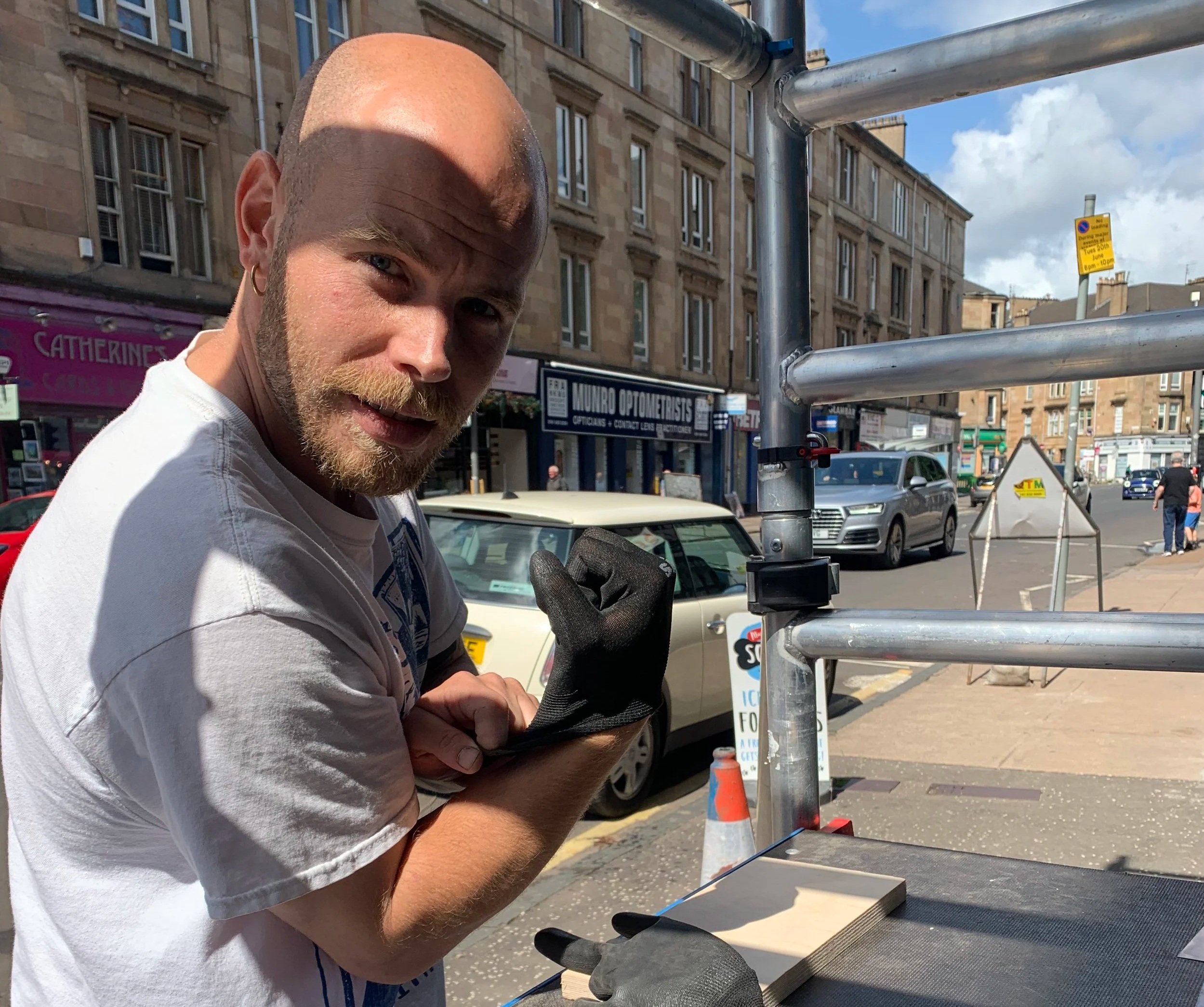 A sign maker, installing a custom made sign on a shop front.