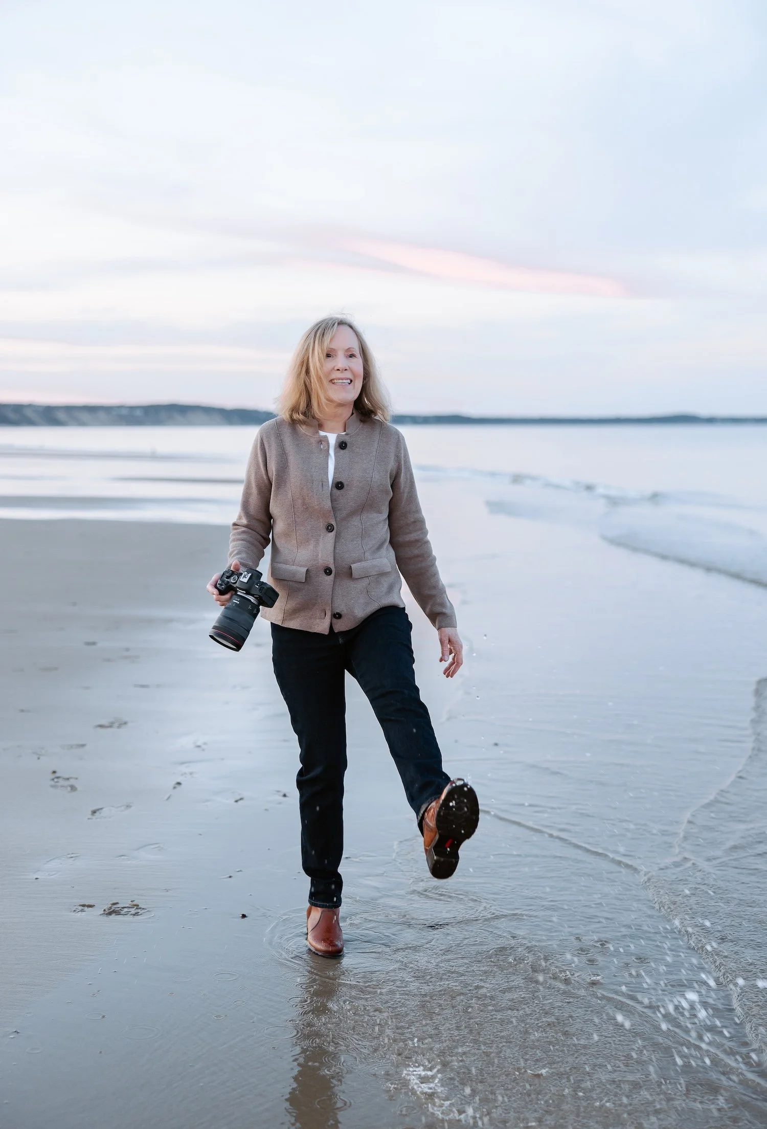 smiling photographer kicking at water at beach