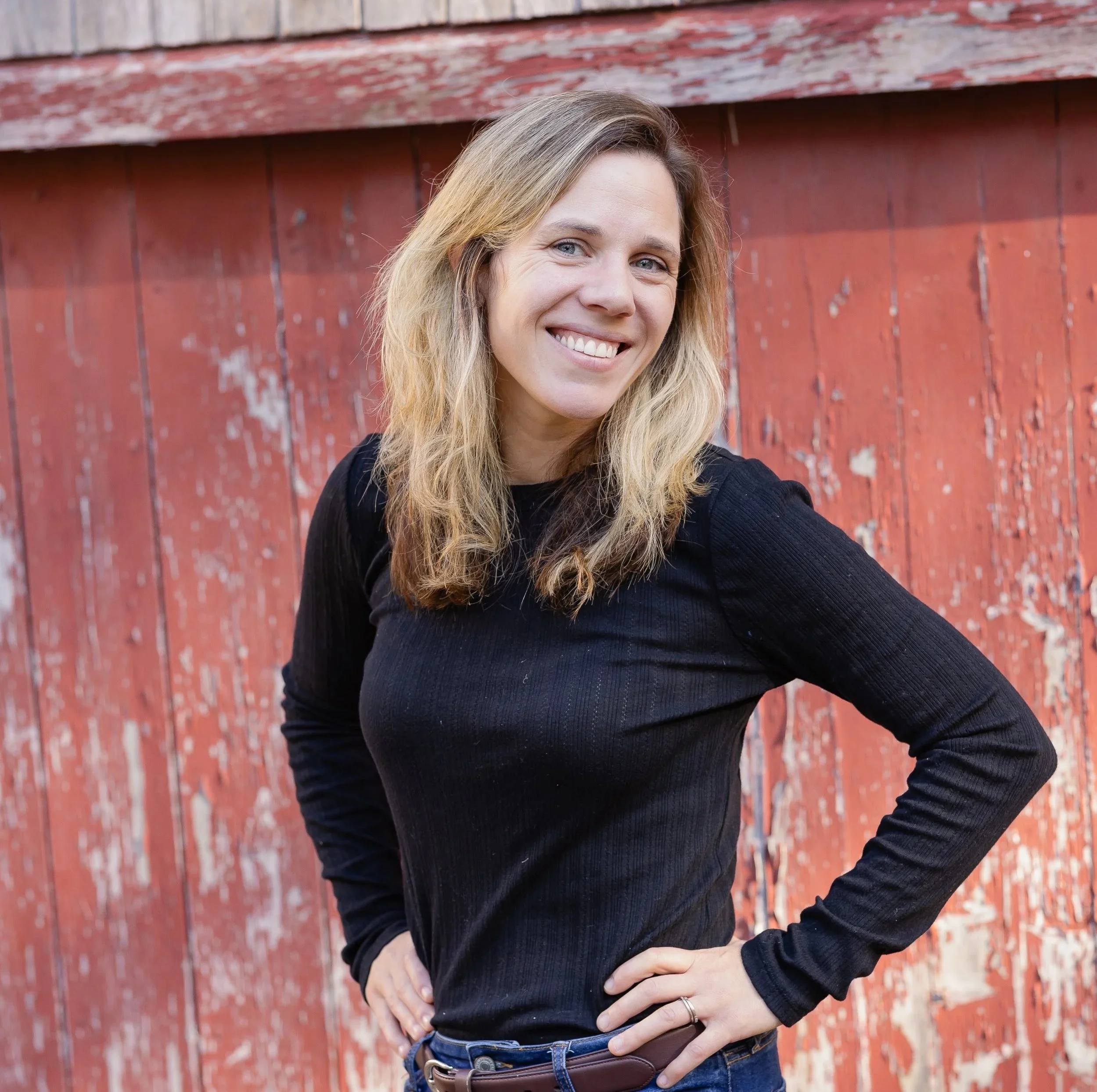 smiling woman in front of red barn door