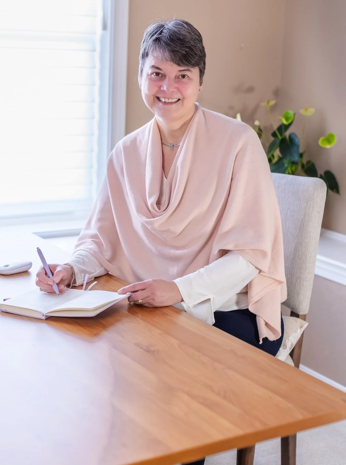 smiling woman in pink shawl journaling