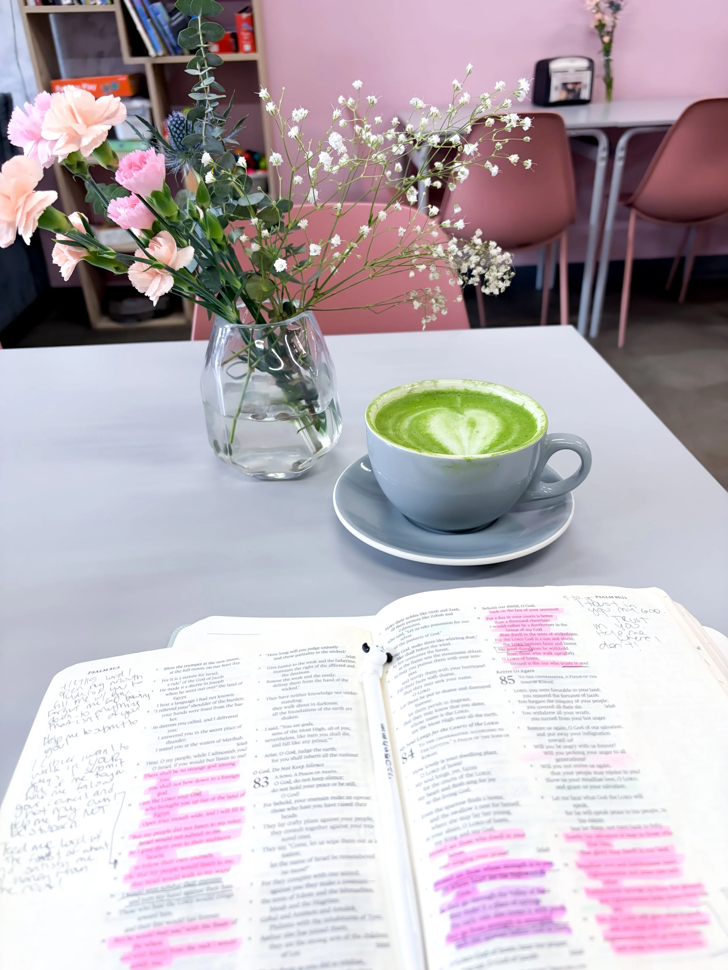 Bible and hot matcha in a cute pink coffee shop with beautiful flowers