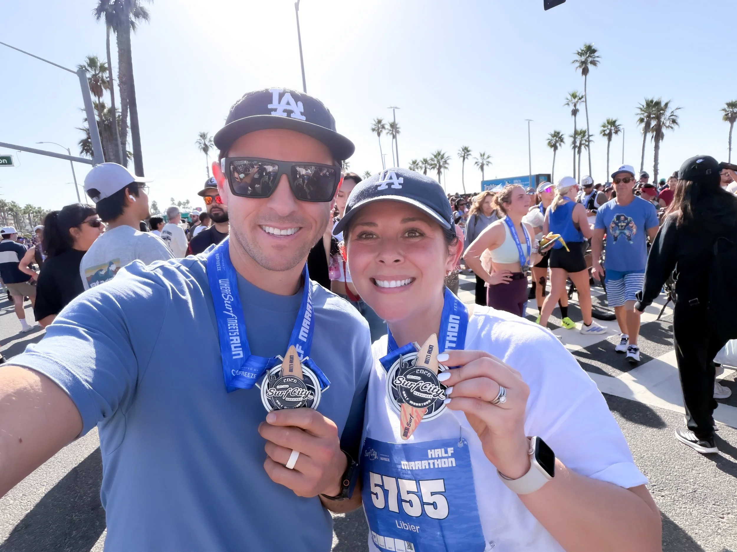 Smiling runners holding a finisher medal at the Surf City Half Marathon finish line in Huntington Beach.